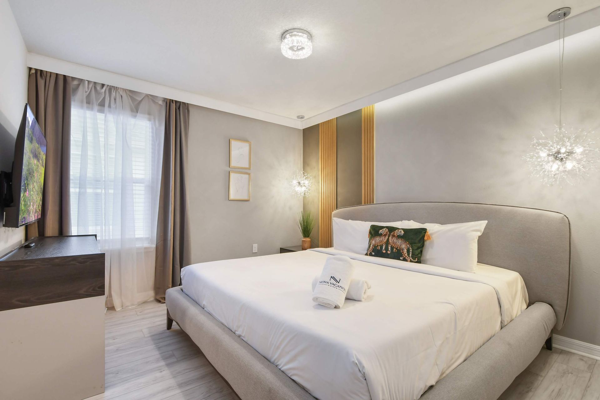 Cozy modern bedroom with king bed, elegant lighting, and a mounted smart TV.