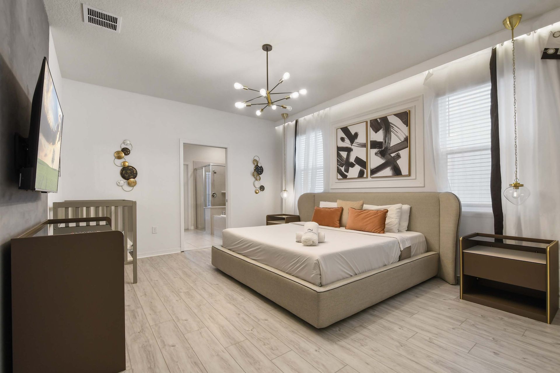 Stylish suite with king bed, smart TV, en-suite bath, and cozy crib corner.