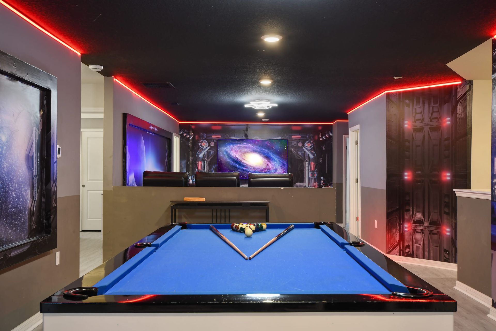 Cosmic-themed game room with blue pool table, LED lighting, and galactic murals.