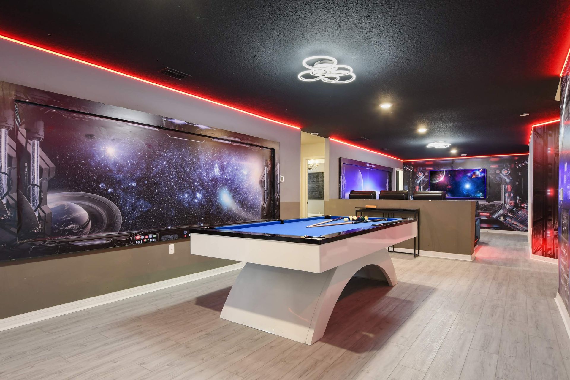 Sleek space-themed game room with modern pool table, LED trim, and cosmic murals.