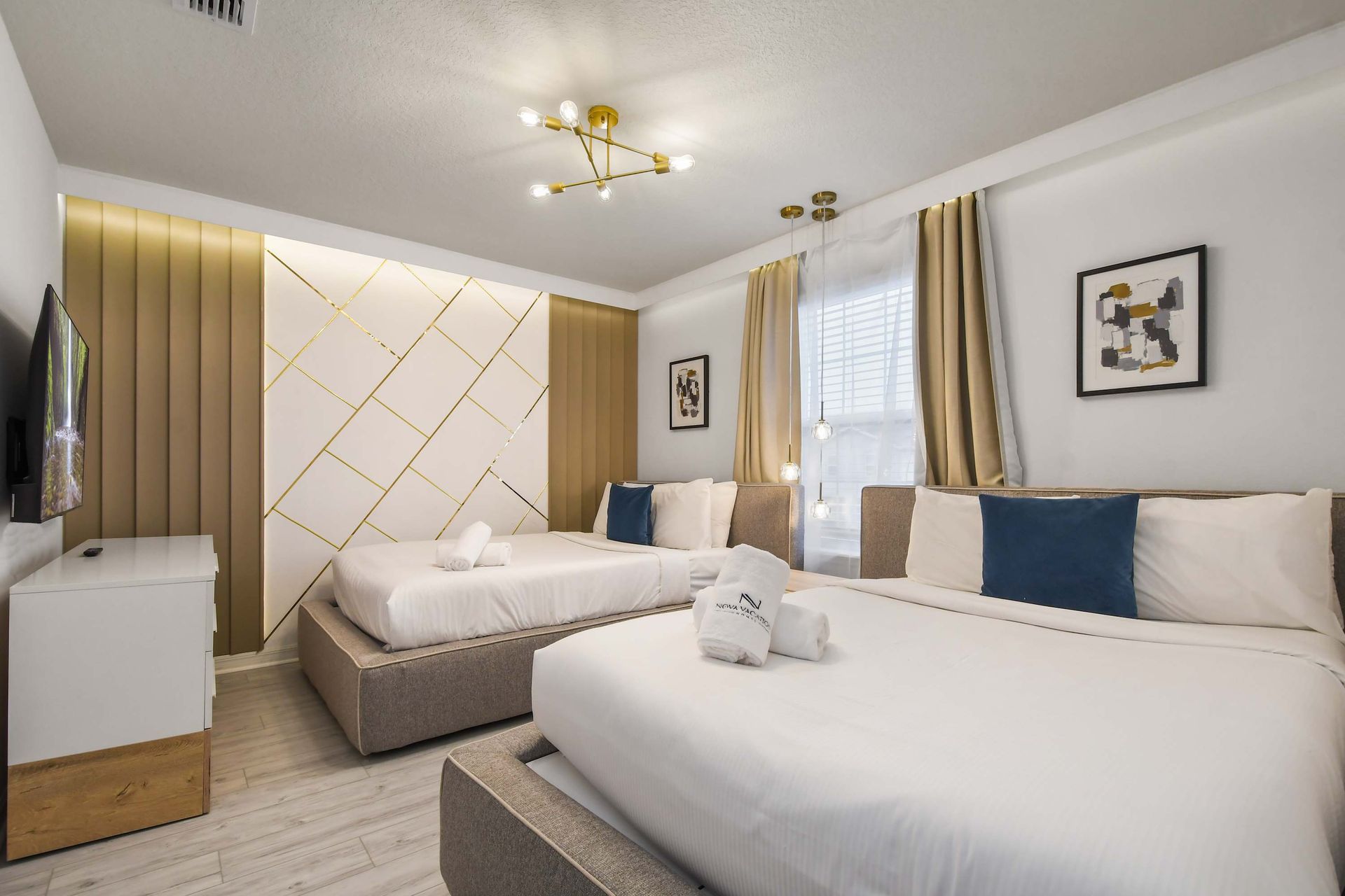 Modern double bedroom with two queen beds, stylish accents, and a smart TV.