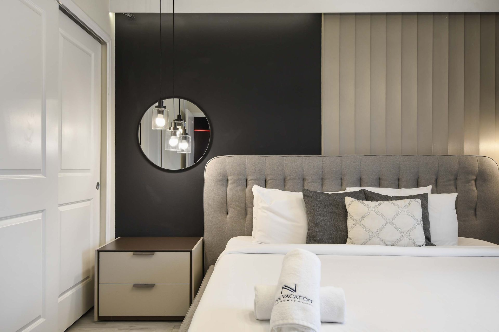 Elegant bedroom with tufted king bed, modern pendant lights, and chic decor.