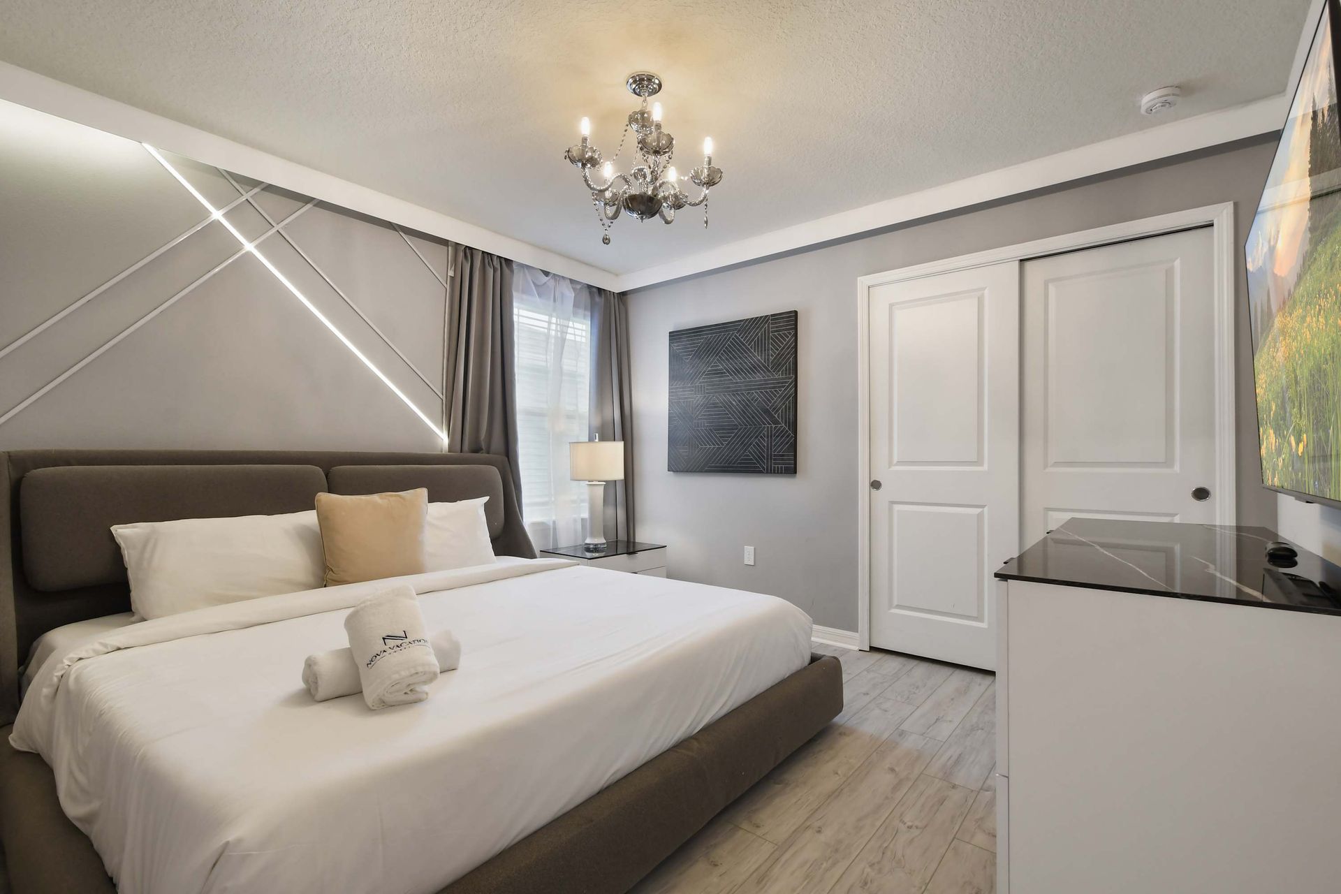 Refined bedroom with king bed, statement chandelier, and sleek modern finishes.