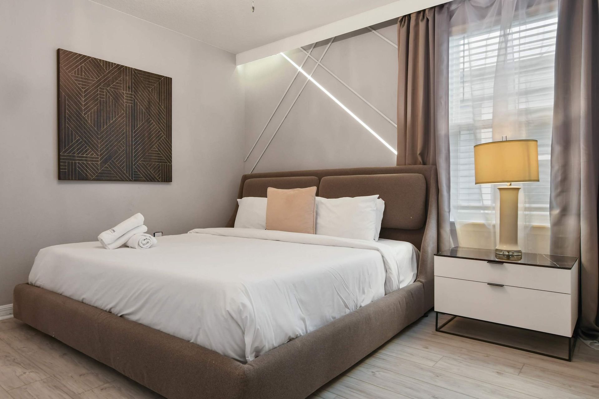 Modern king bedroom with sleek decor, warm lighting, and geometric accent wall.