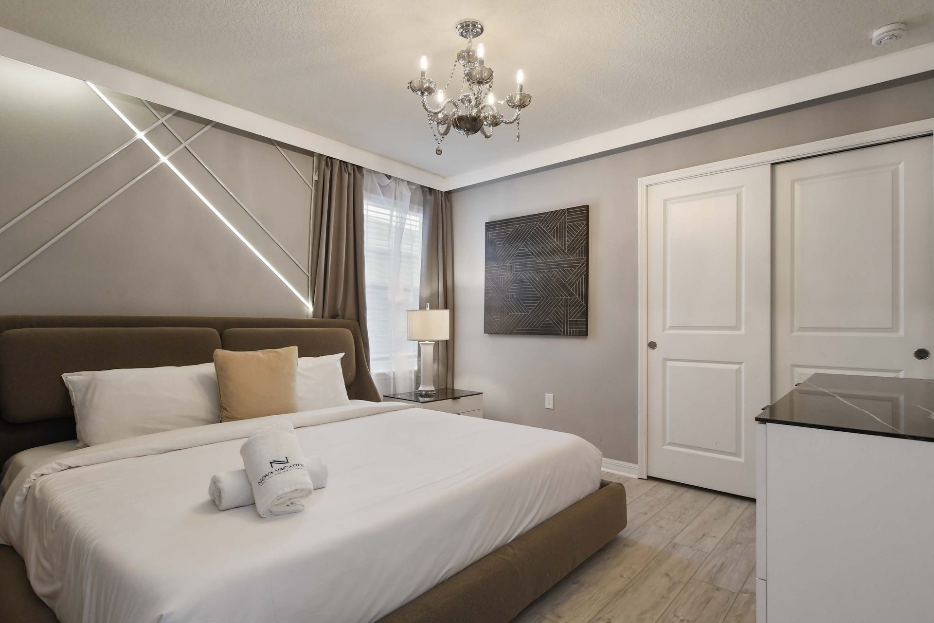 Chic bedroom with king bed, elegant chandelier, and stylish modern wall accents.