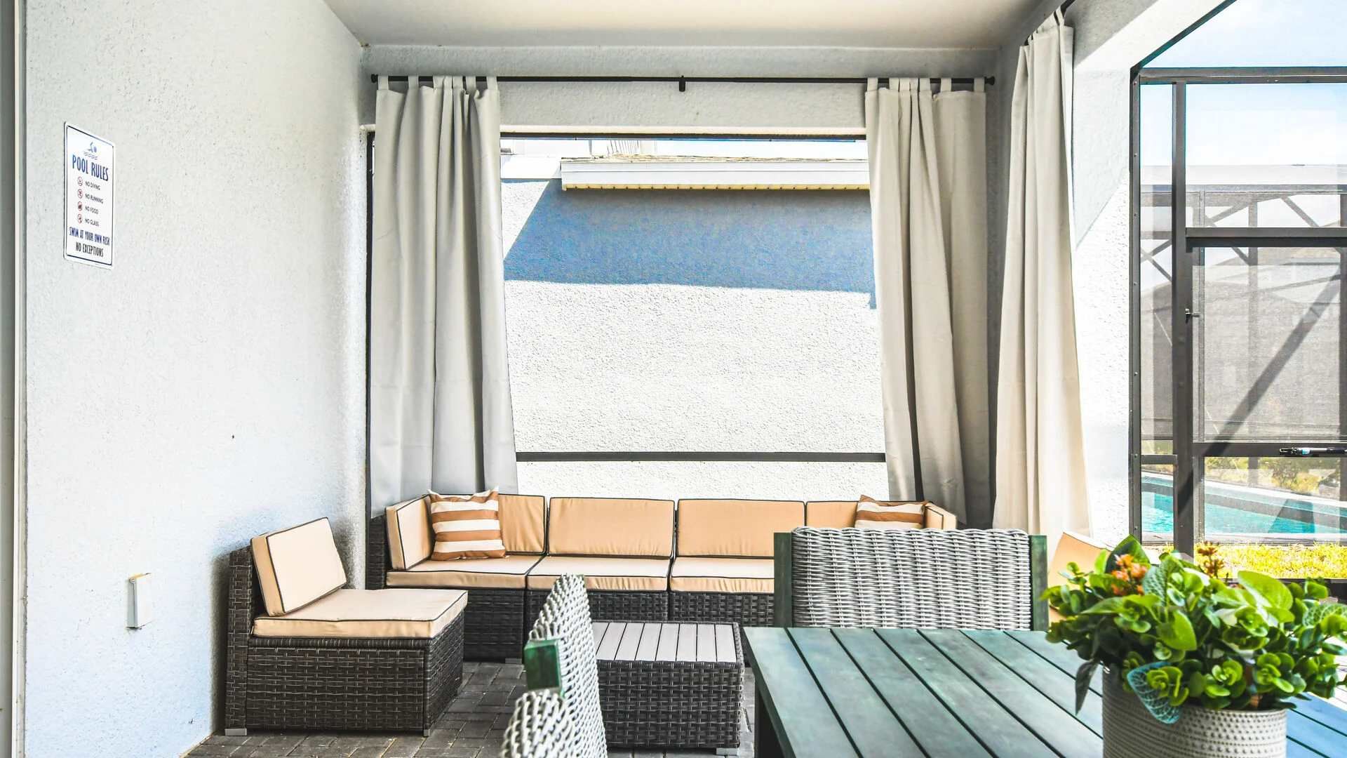 Relaxing outdoor nook with sectional seating, privacy curtains, and poolside charm.