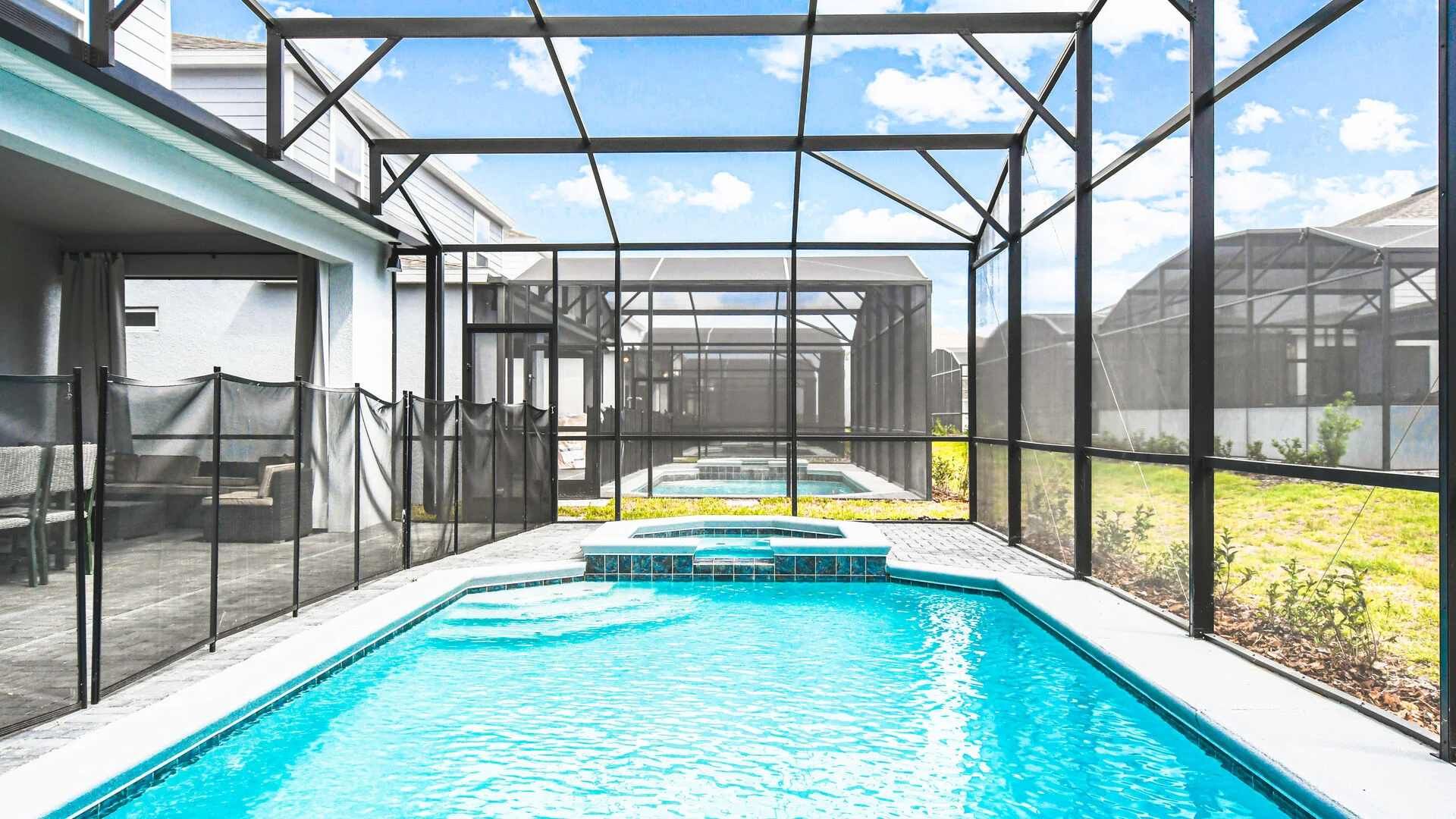 Screened-in private pool and spa with safety fence, lounge area, and sunny views.