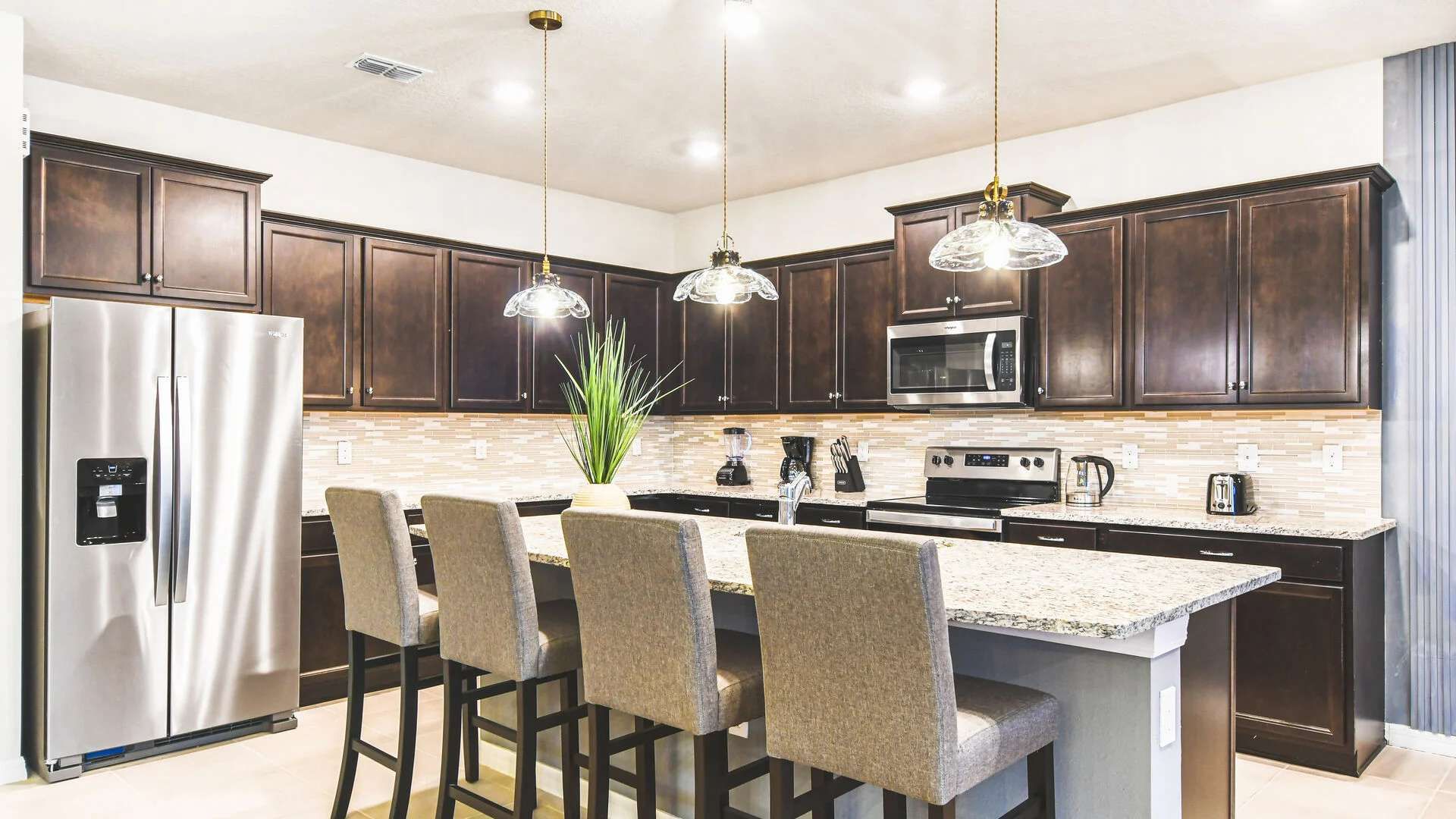 Modern kitchen with granite island, stainless steel appliances, and seating.