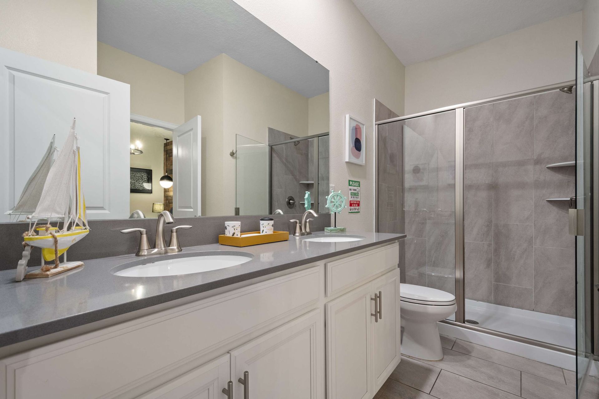 Modern bathroom with sleek double vanity, spacious glass shower, and coastal-inspired touches!