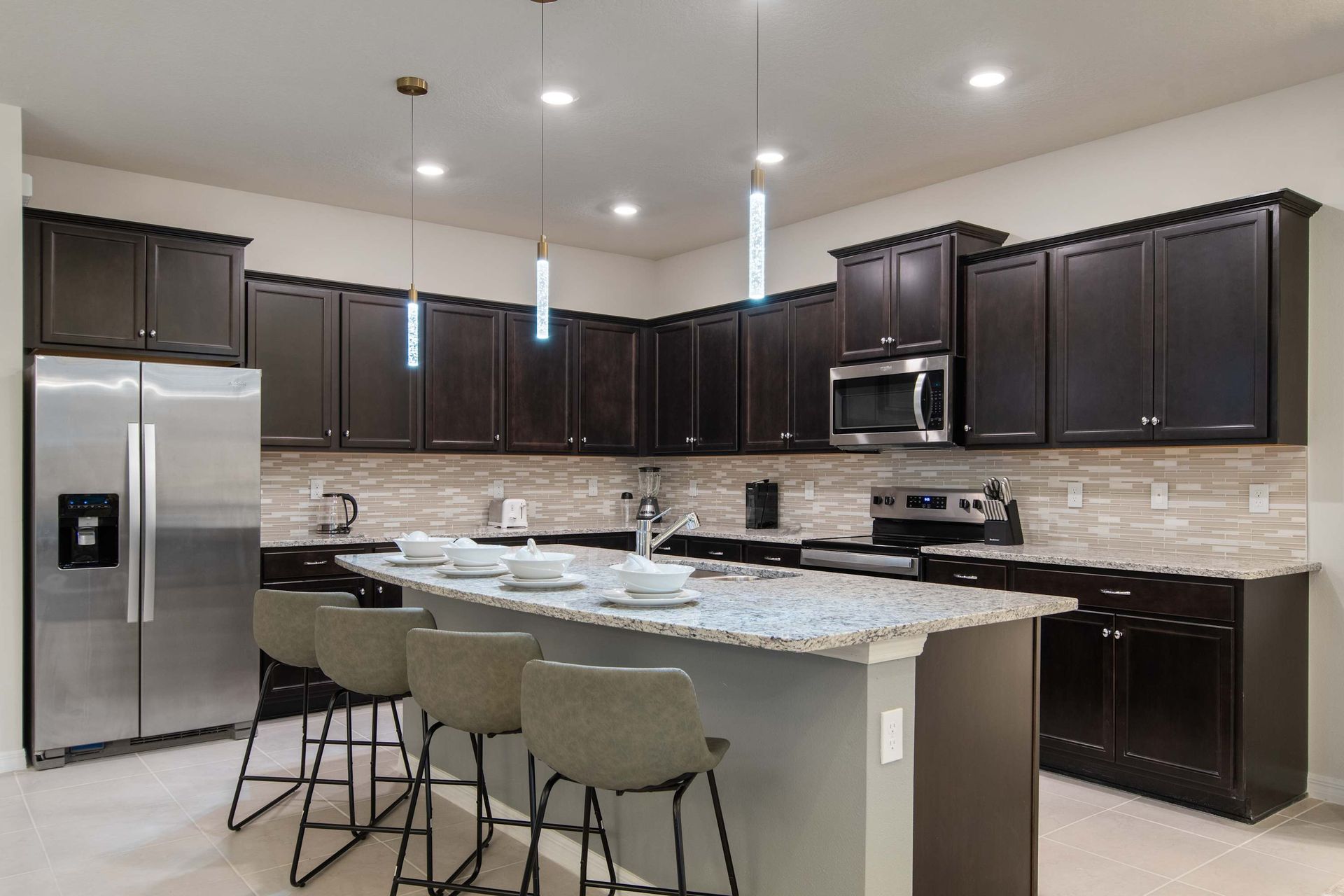 Stylish kitchen with granite counters, sleek cabinets, and modern pendant lights.