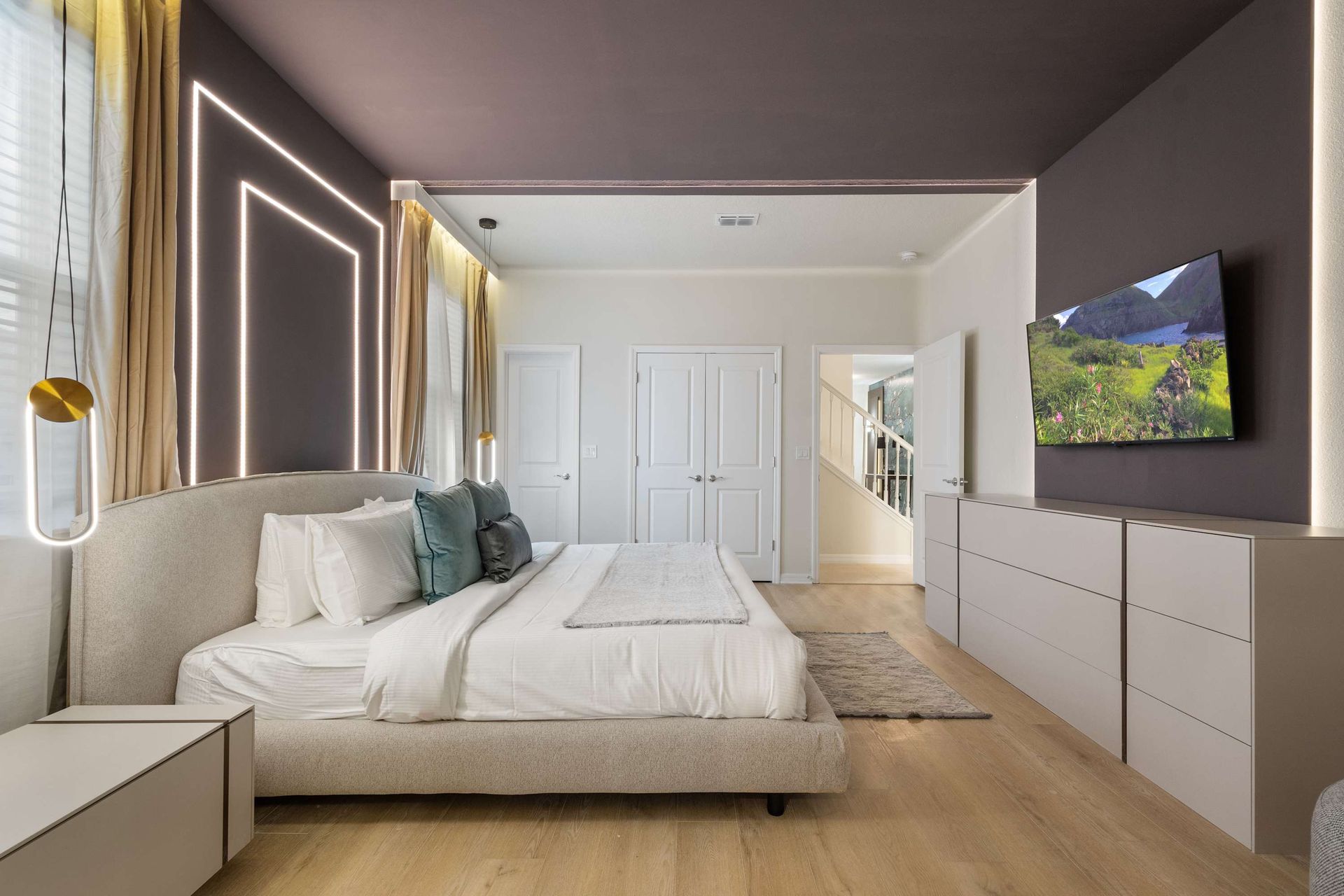 Sleek modern suite with LED-lit accent wall, king bed, and large smart TV.