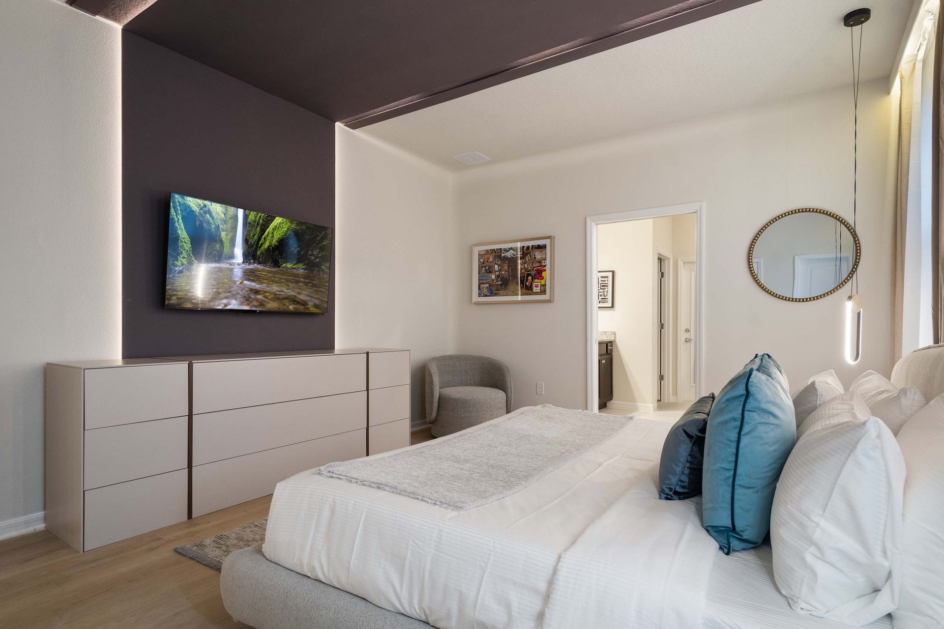 Modern bedroom with cozy textures, ambient lighting, and ensuite bathroom access.