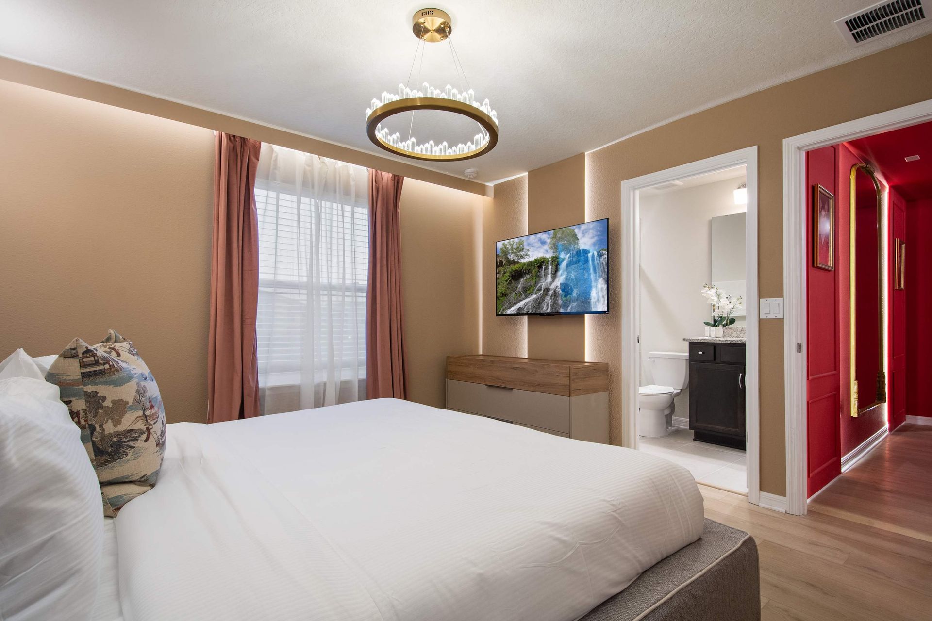 Warm and inviting bedroom with ensuite bath, smart TV, and elegant lighting.