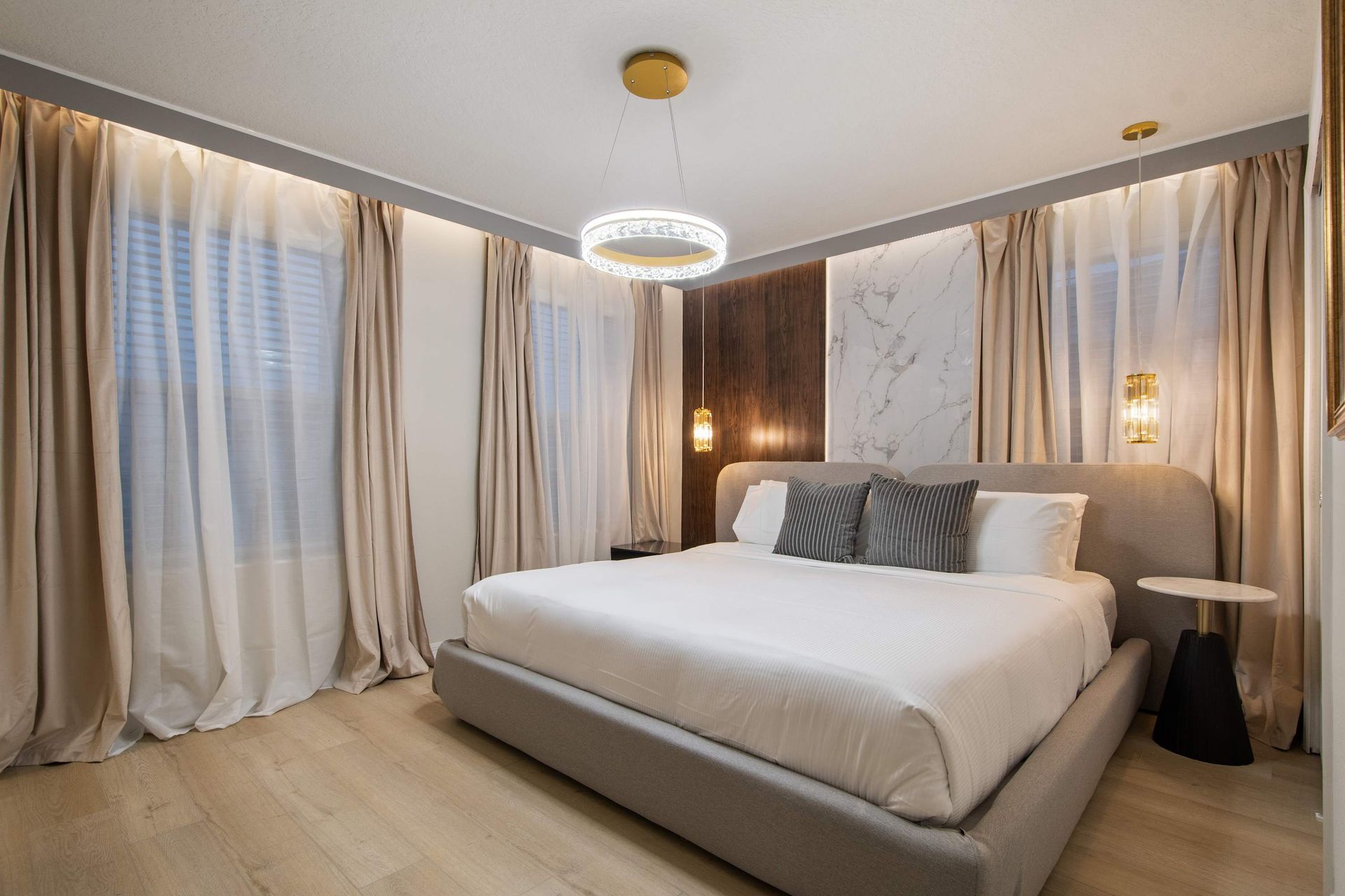 Modern luxury bedroom with king bed, marble accents, and elegant ambient lighting.