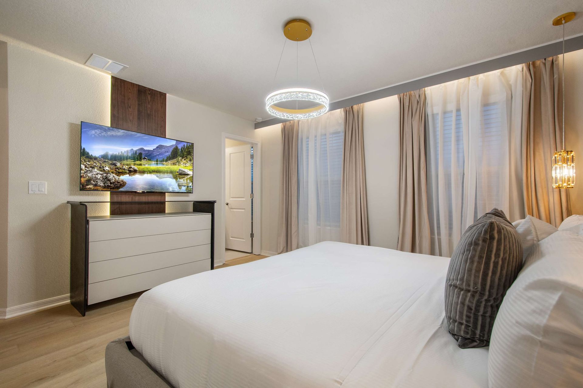 Bright and elegant bedroom with king bed, smart TV, and luxurious lighting.