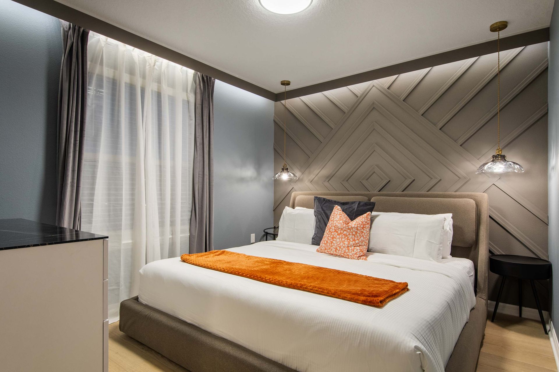 Stylish bedroom with modern wood accent wall, cozy king bed, and soft lighting.