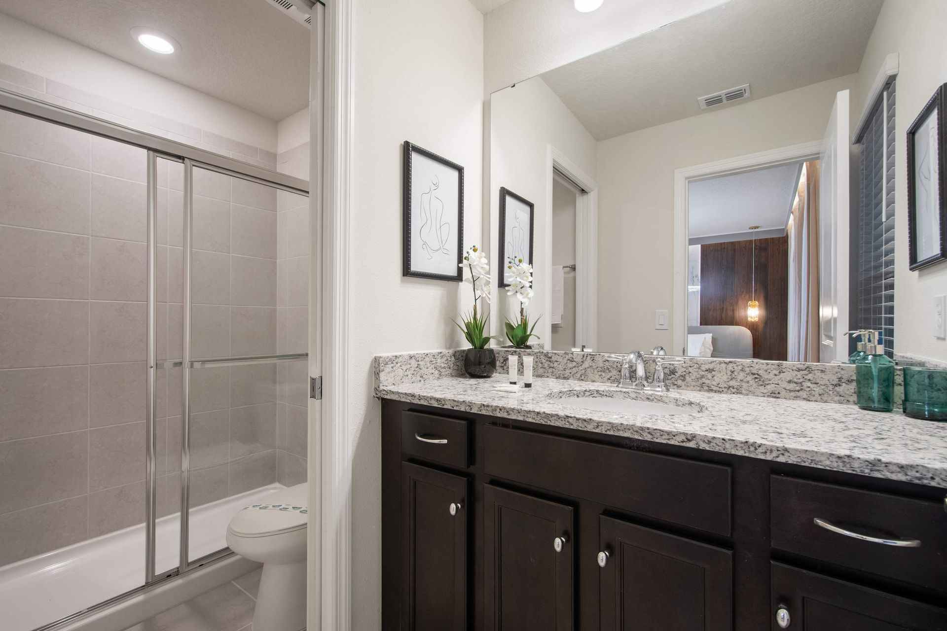 Elegant double-sink bathroom with granite counters and modern walk-in shower.