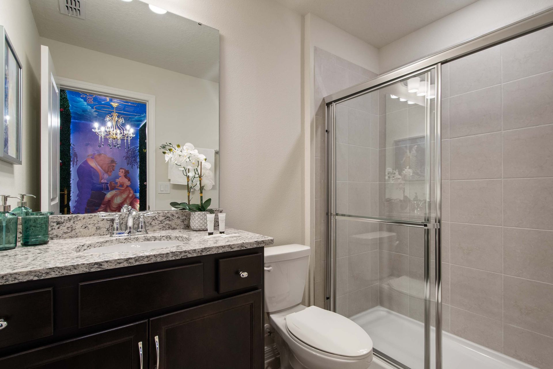 Modern bathroom with glass shower, granite vanity, and themed suite access.