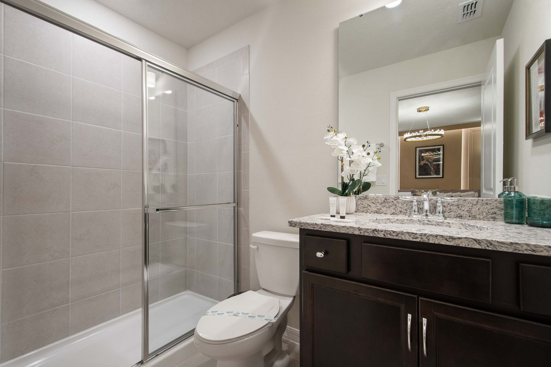 Modern bathroom with granite counters and a spacious glass walk-in shower.