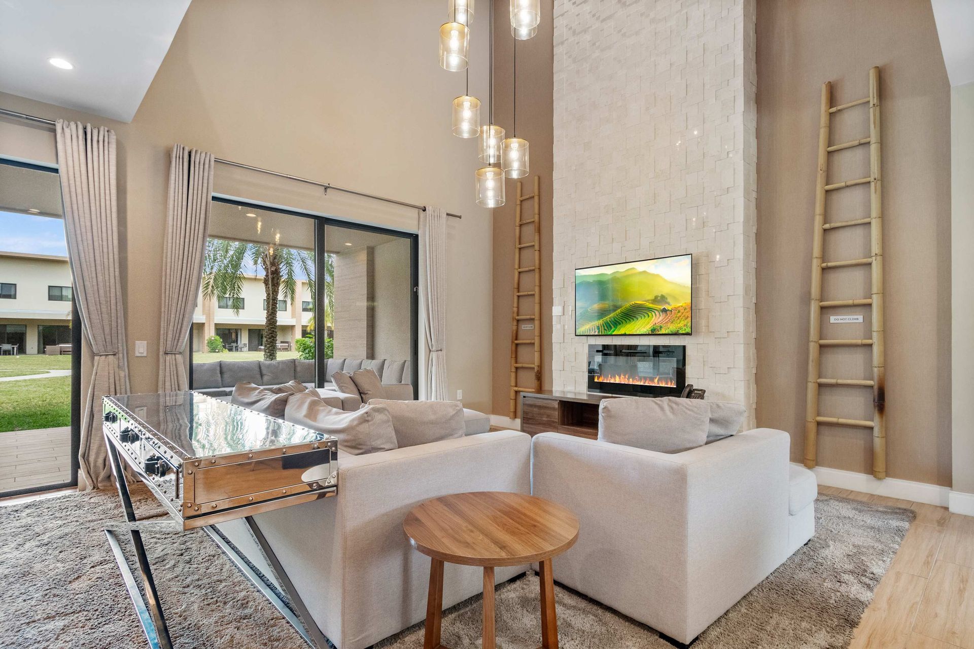 Bright, airy living room with high ceilings, modern fireplace, and outdoor views
