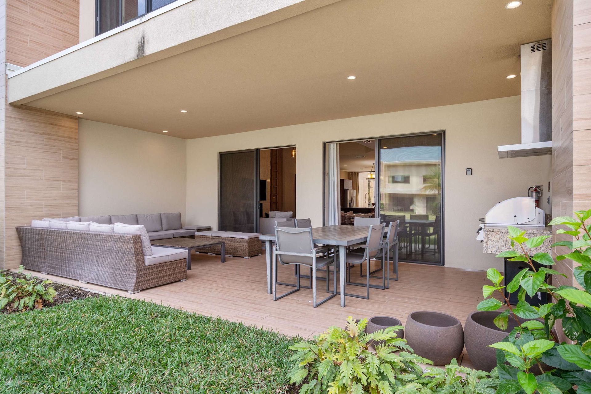 Covered patio with lounge seating, dining area, and built-in grill for relaxing
