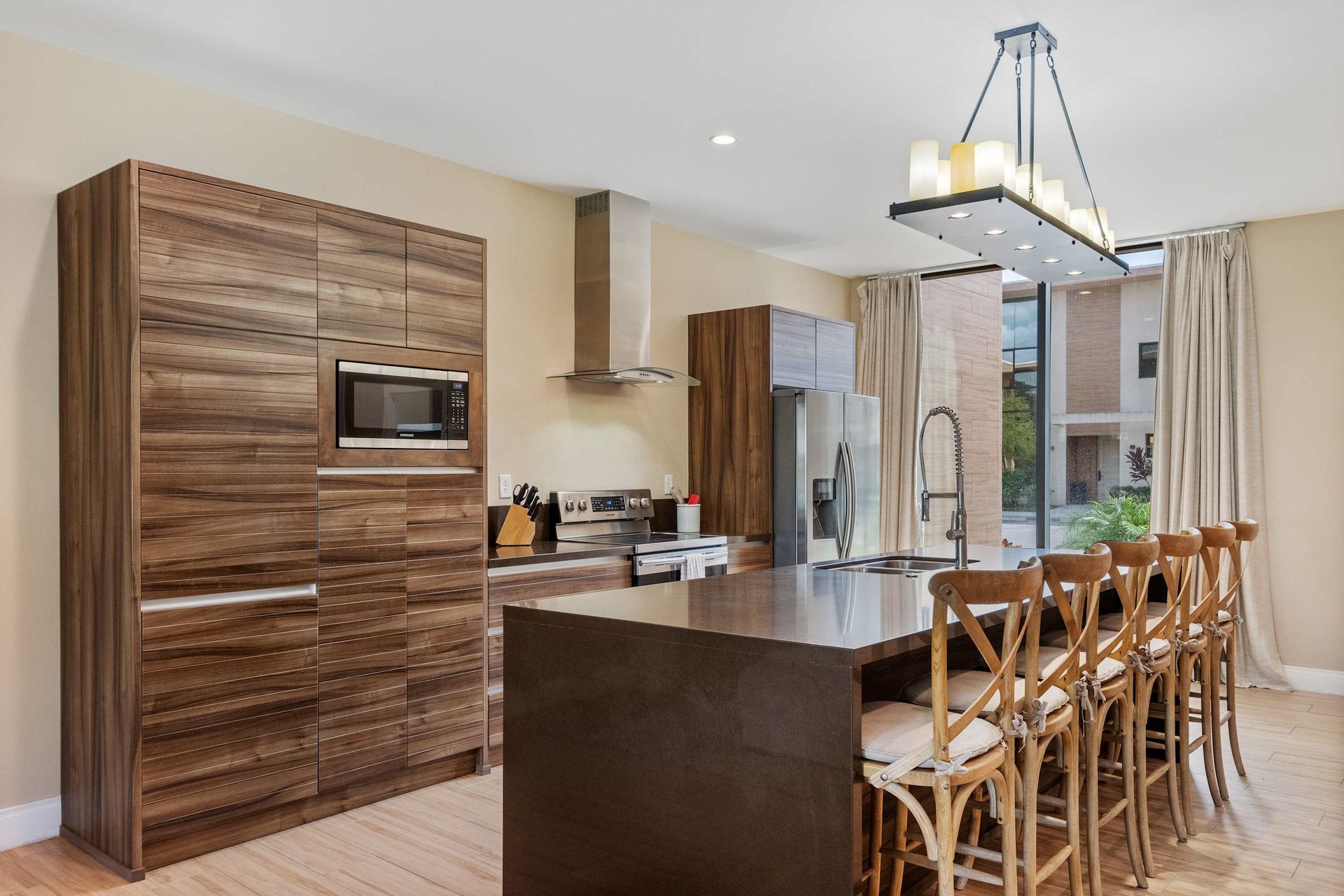 Gourmet kitchen with wood cabinetry, large island, and designer lighting fixture
