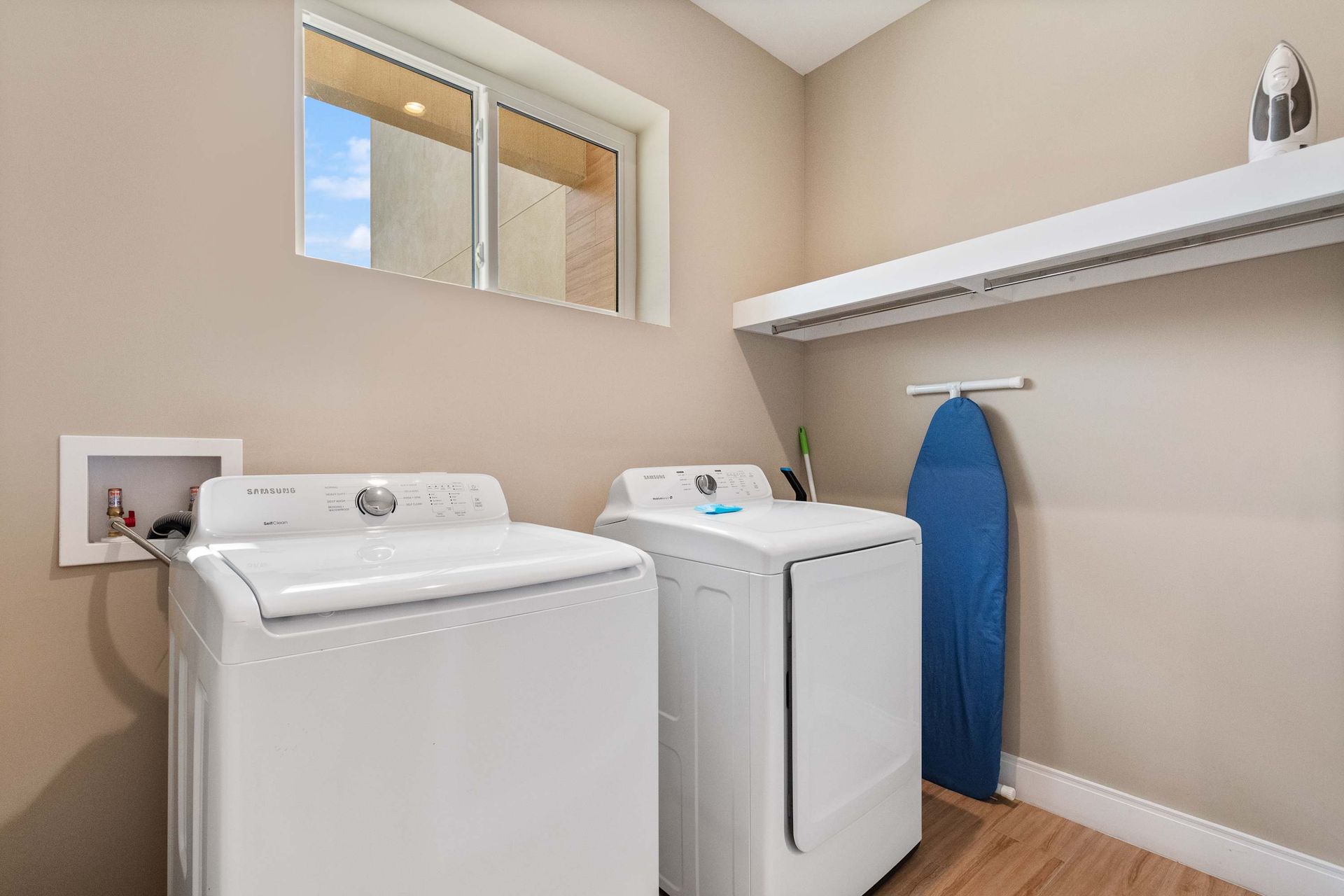 Convenient laundry room with washer, dryer, natural light, and built-in storage shelf
