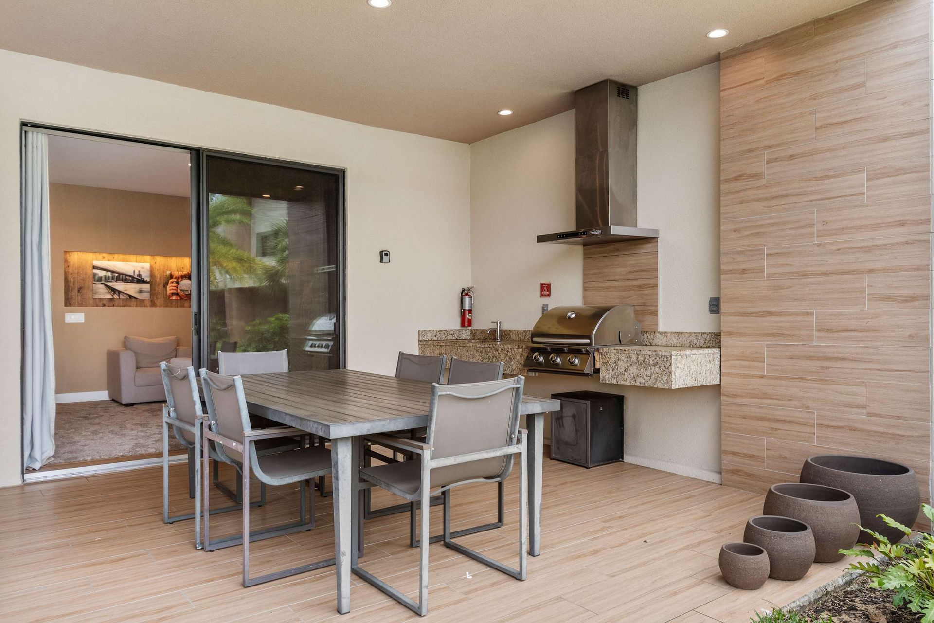 Outdoor dining space with built-in grill, modern furnishings, and seamless indoor access
