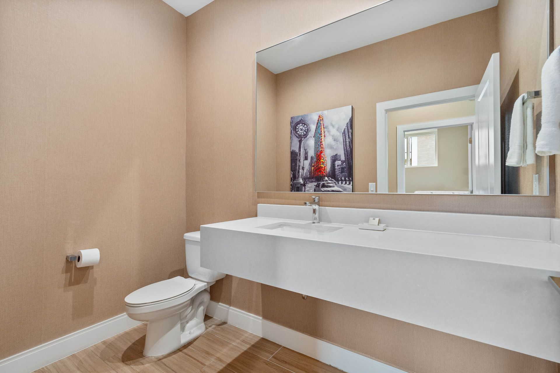 Modern half bath with sleek floating vanity, large mirror, and warm neutral palette
