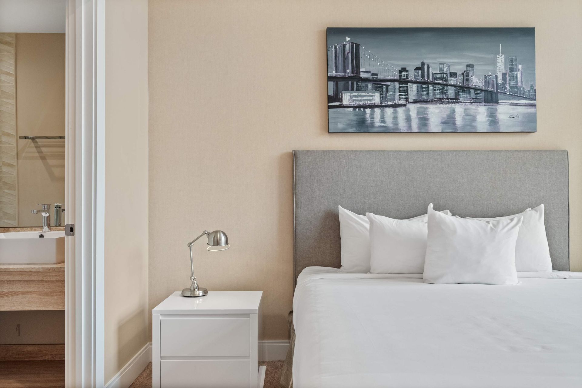 Minimalist bedroom with king bed, sleek lighting, and en-suite bathroom access
