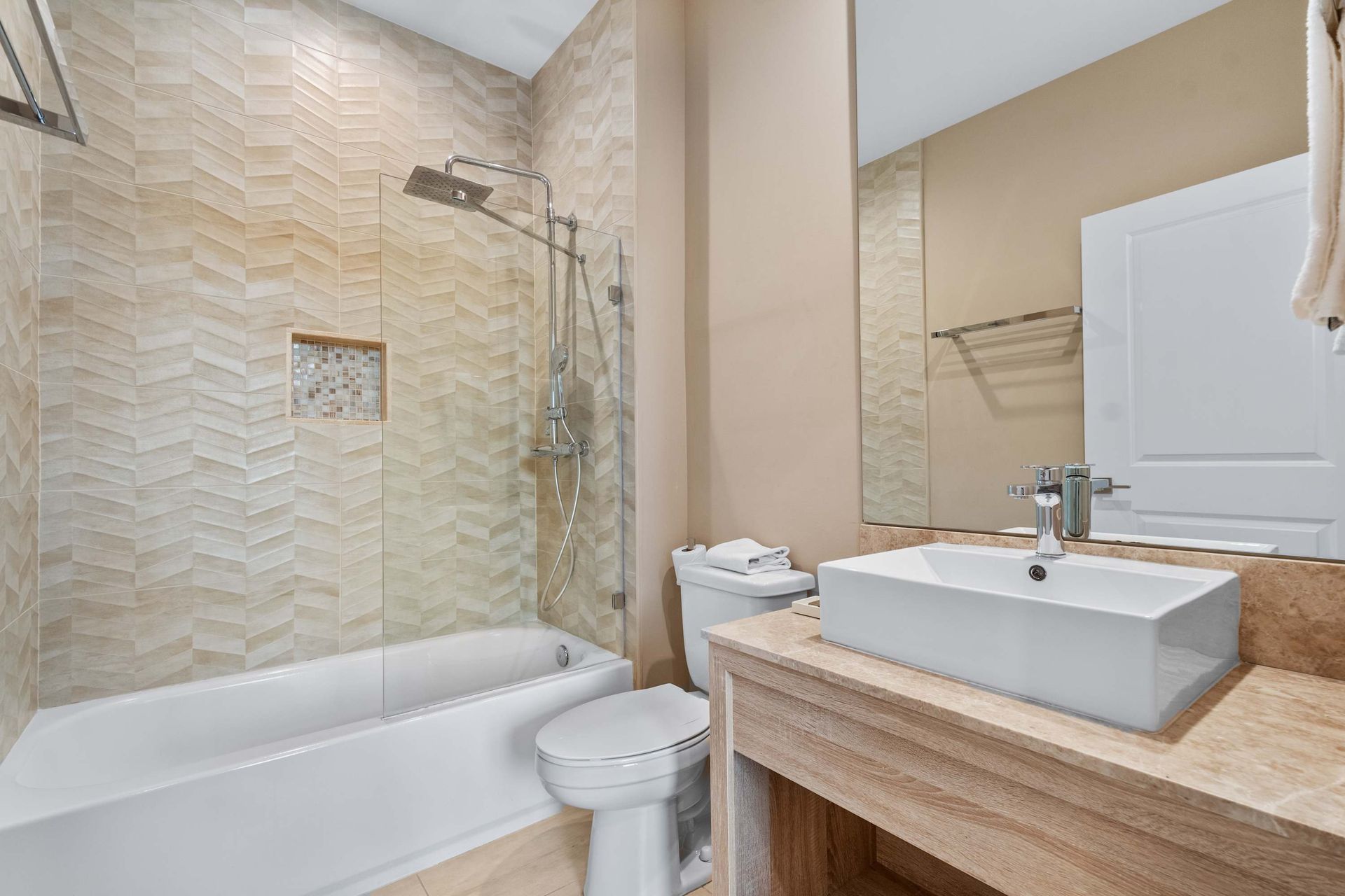 Stylish bathroom with modern vanity, vessel sink, and chic tile shower-tub combo
