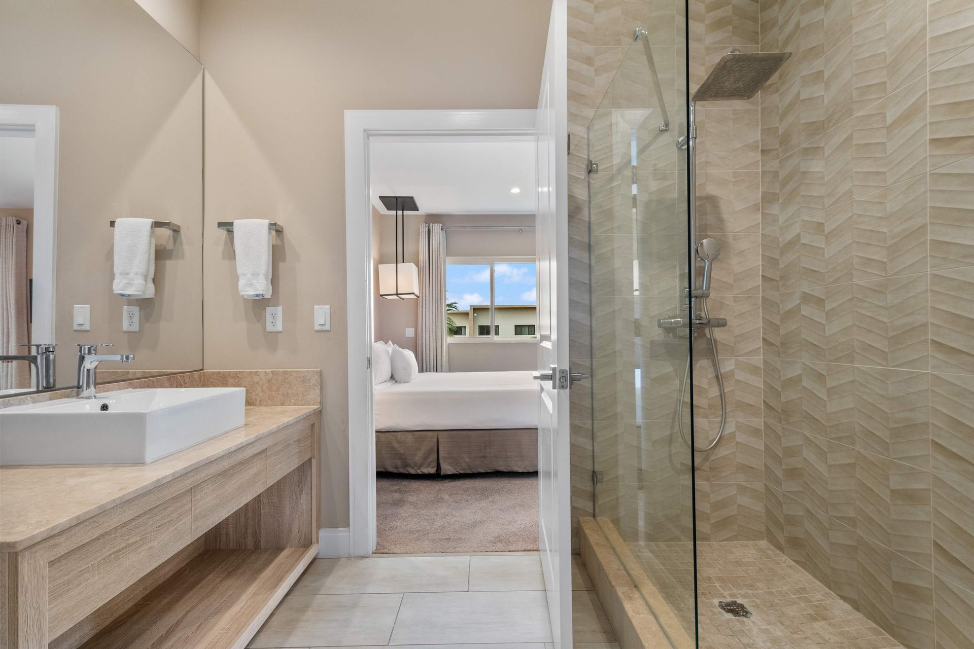 Elegant en-suite bathroom with walk-in glass shower, modern vanity, and warm tones
