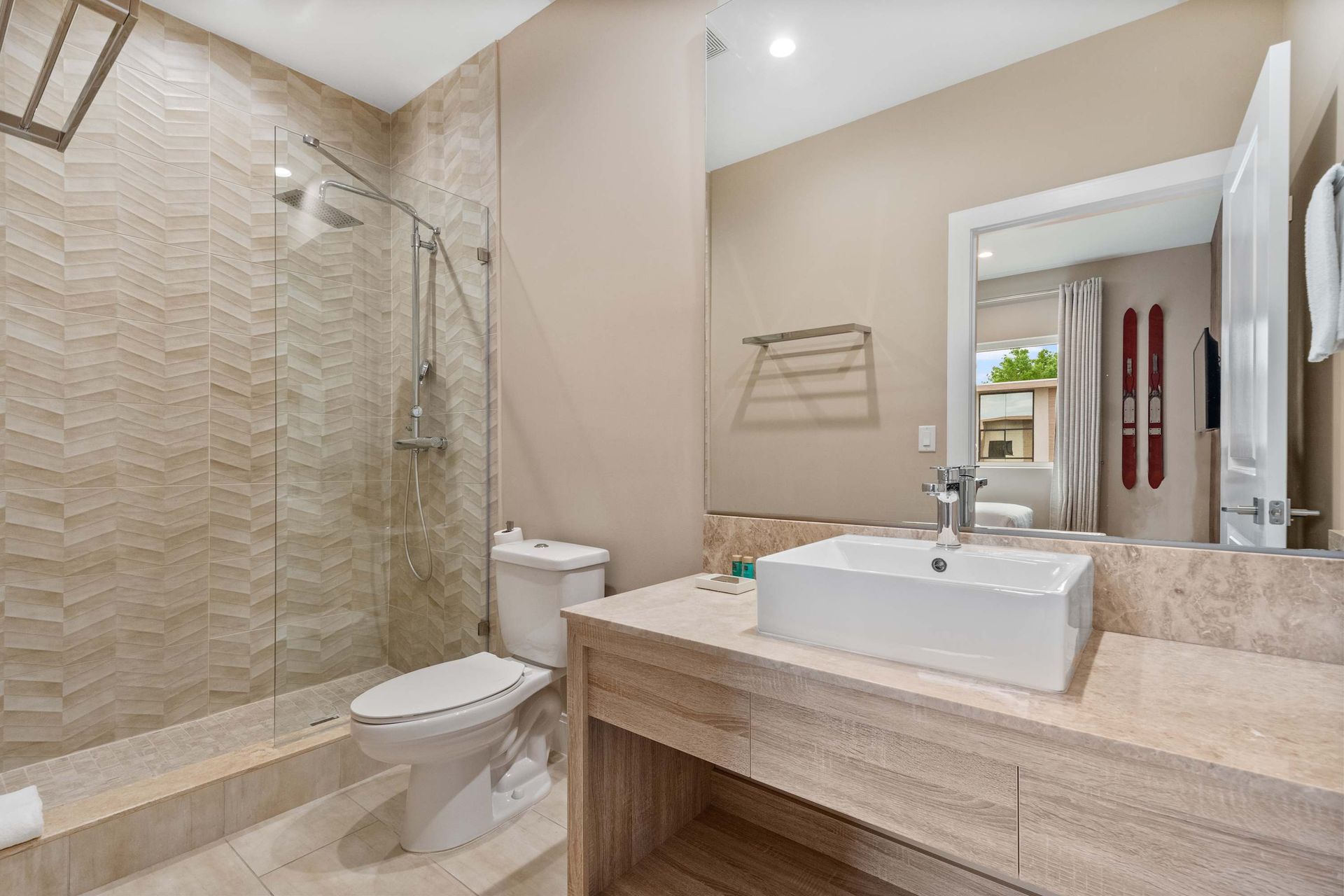 Modern bathroom with walk-in glass shower, vessel sink, and elegant tile finishes
