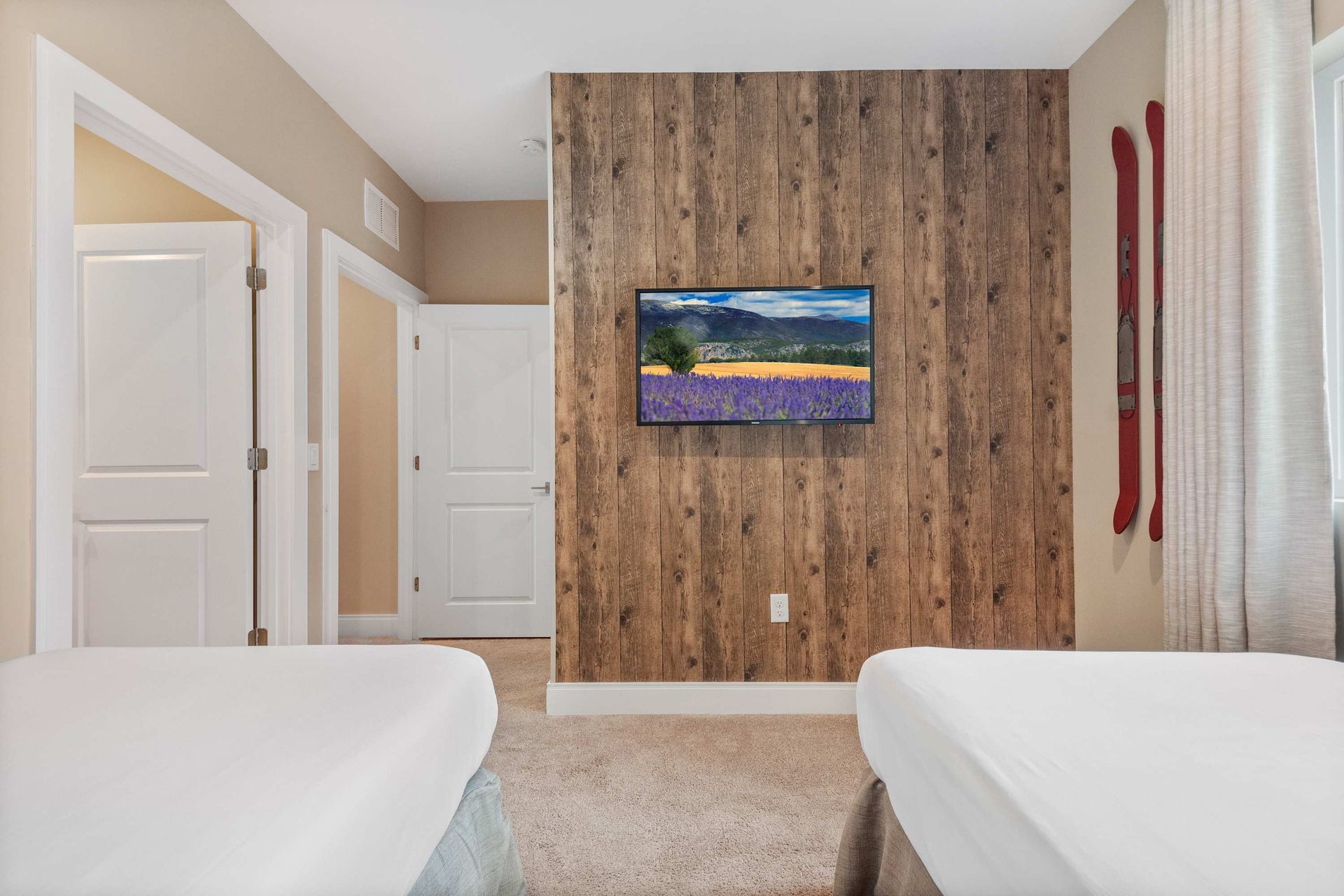 Rustic twin room with wood accent wall, mounted TV, and charming ski décor
