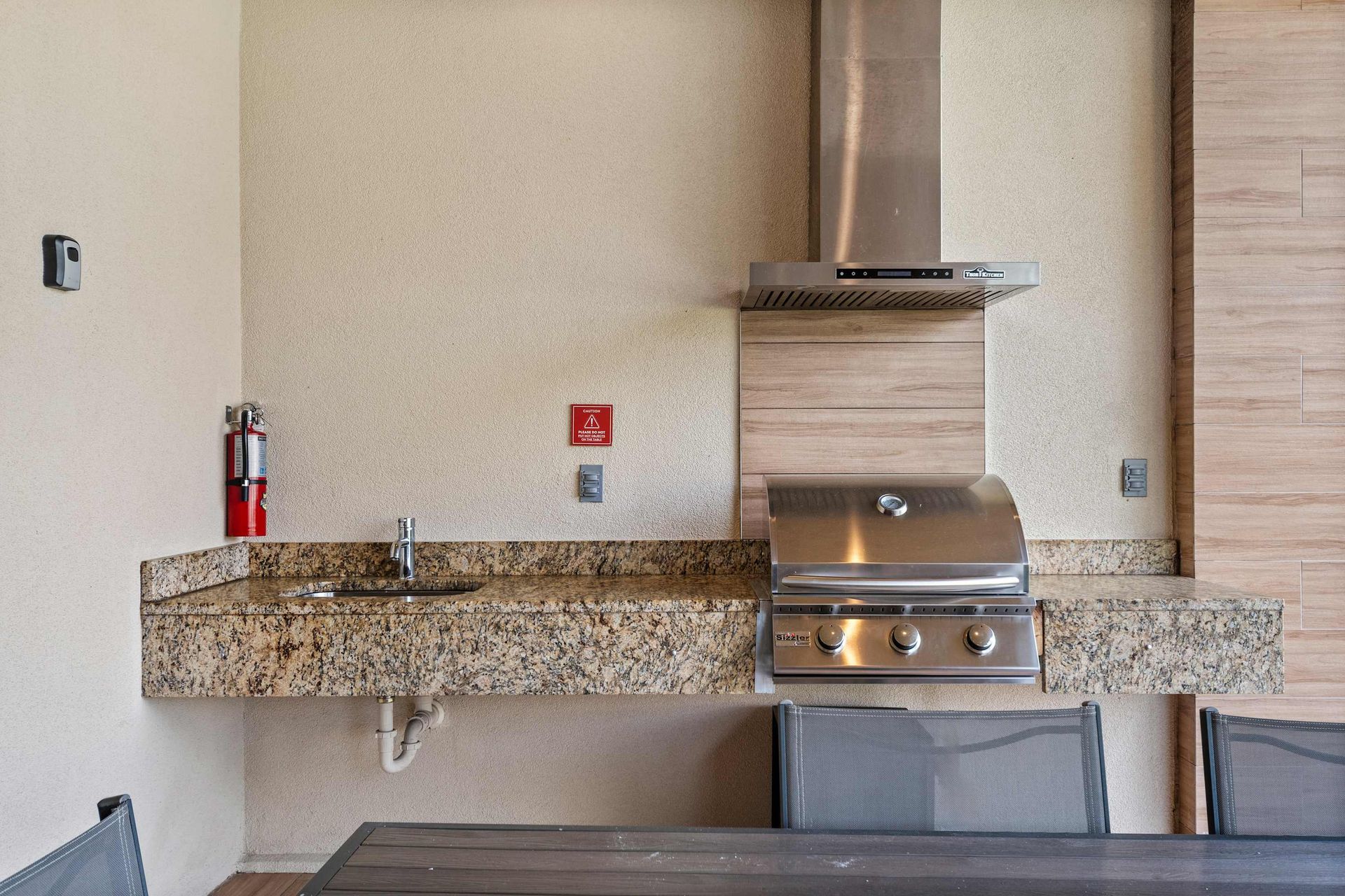 Outdoor kitchen with built-in stainless grill, granite countertops, and sink station
