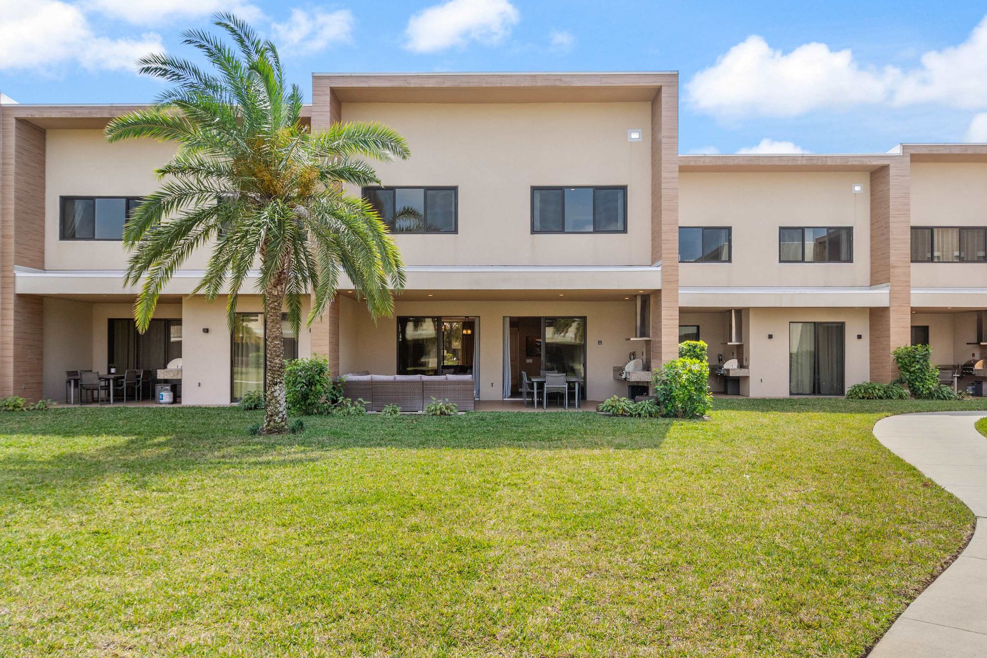 Backyard view of modern townhomes with covered patios and open green space
