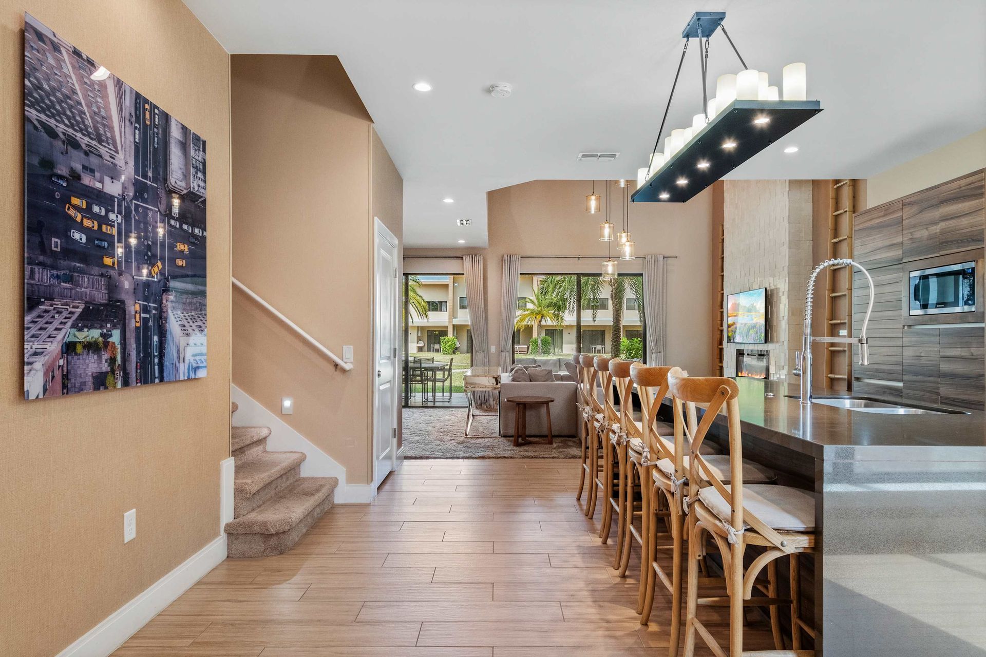 Modern dining and kitchen area with stylish lighting, wood accents, and patio views
