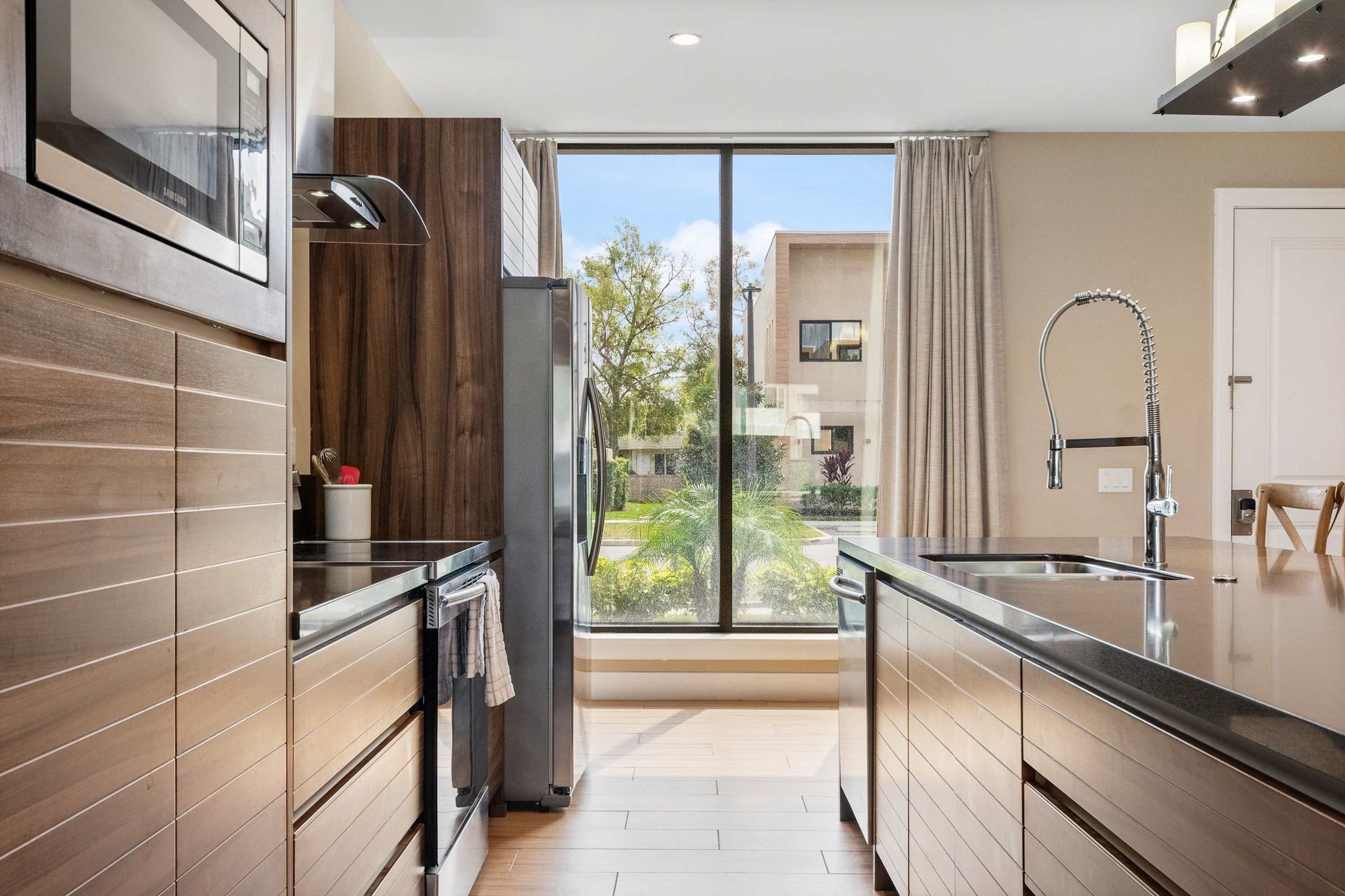 Sleek kitchen with floor-to-ceiling window, modern appliances, and natural light
