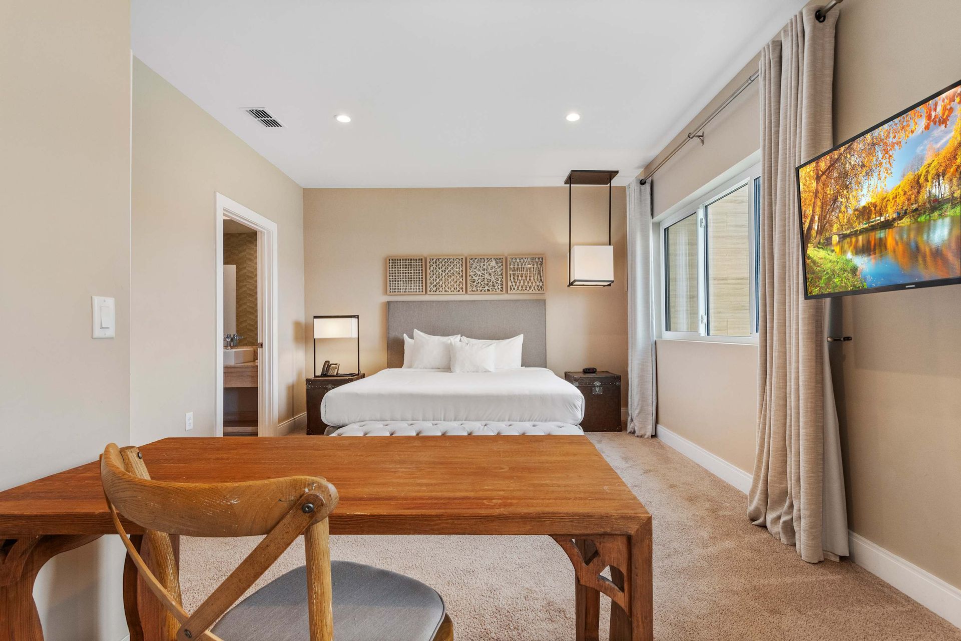 Spacious bedroom with king bed, workspace, natural light, and serene vibes
