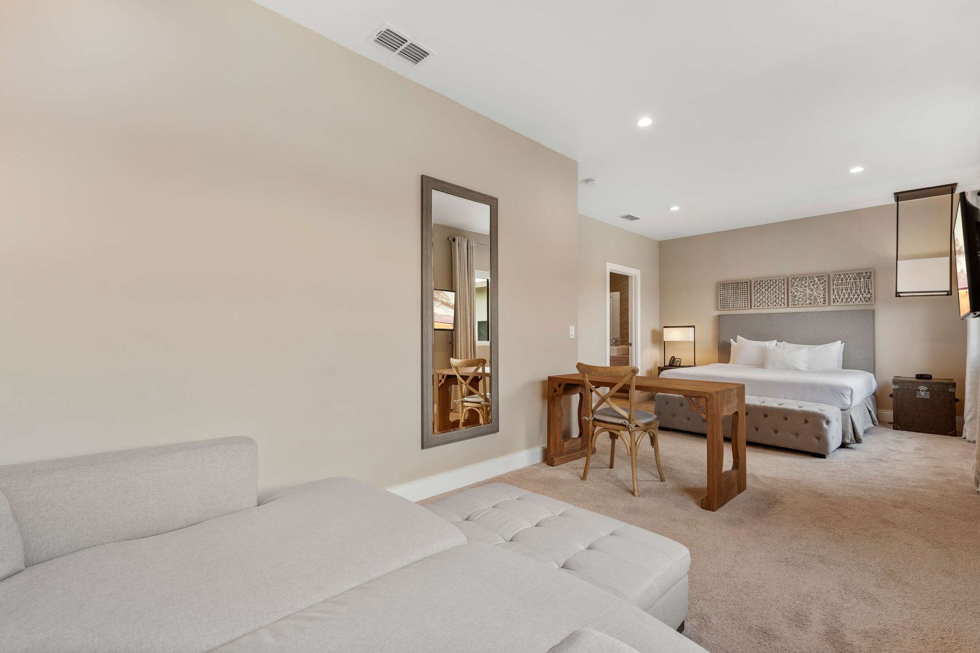 Spacious suite with king bed, lounge area, workspace, and warm neutral tones
