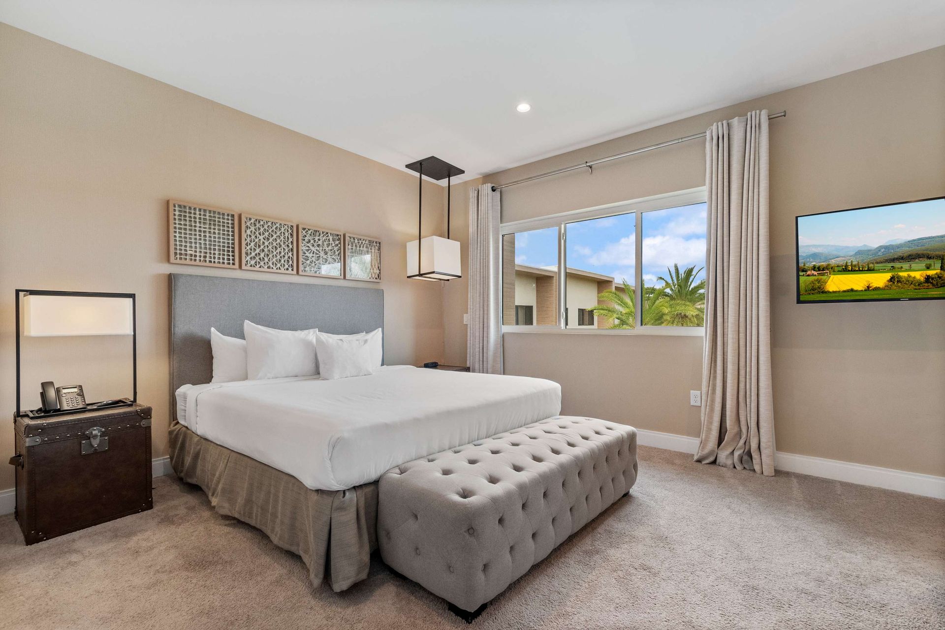 Elegant bedroom with king bed, tufted bench, large window, and serene décor
