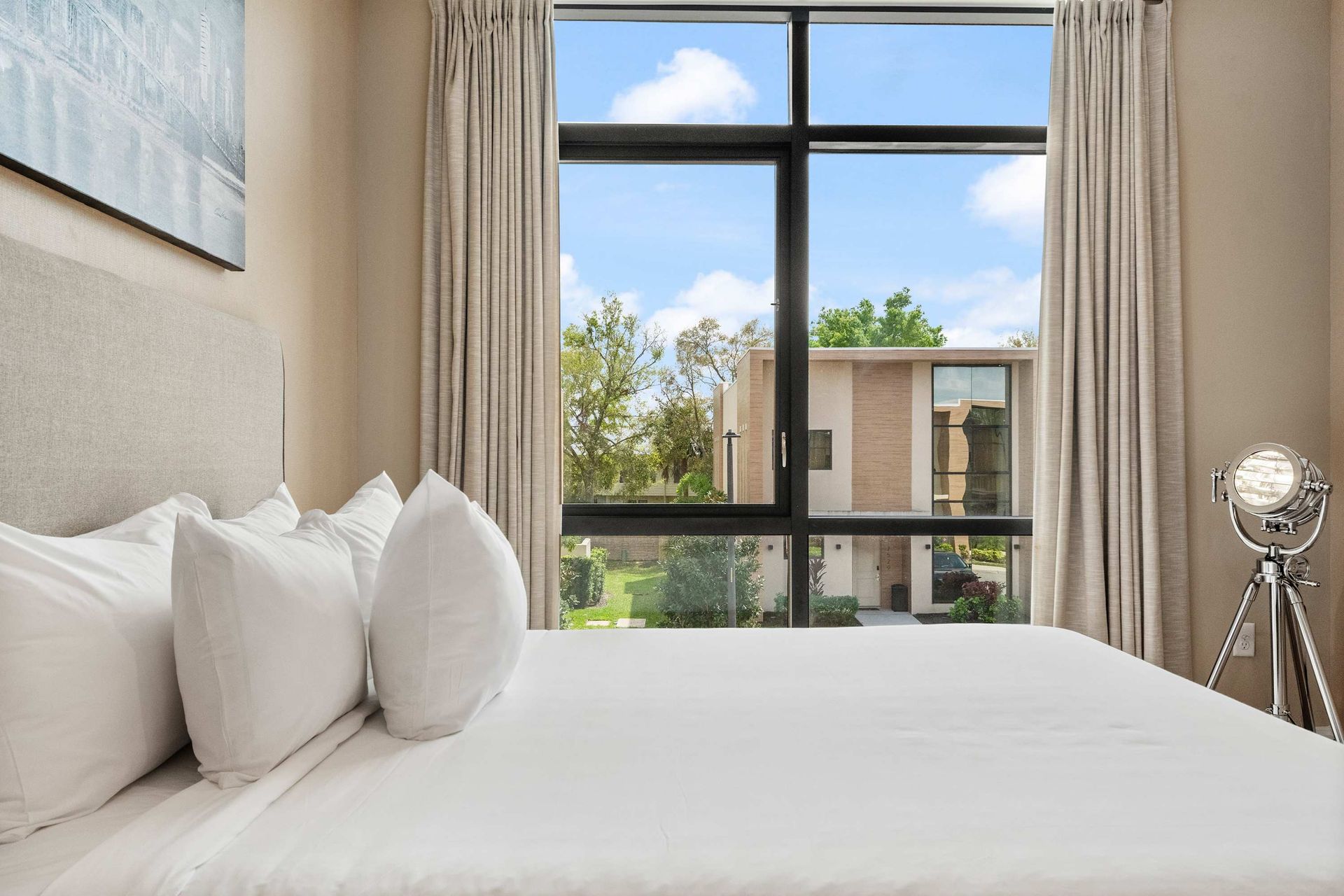 Bright bedroom with plush bedding, large window views, and modern, airy ambiance
