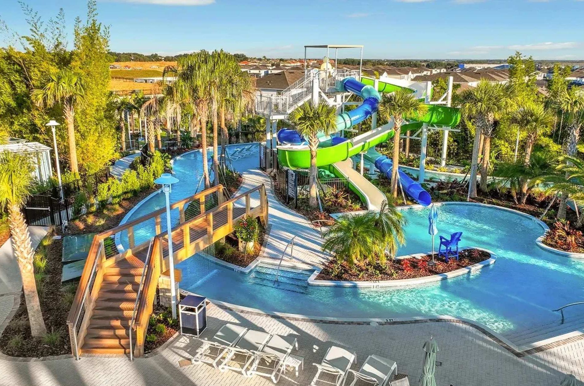 Fun resort pool with twisting waterslides, lazy river, palm trees, and sunny skies
