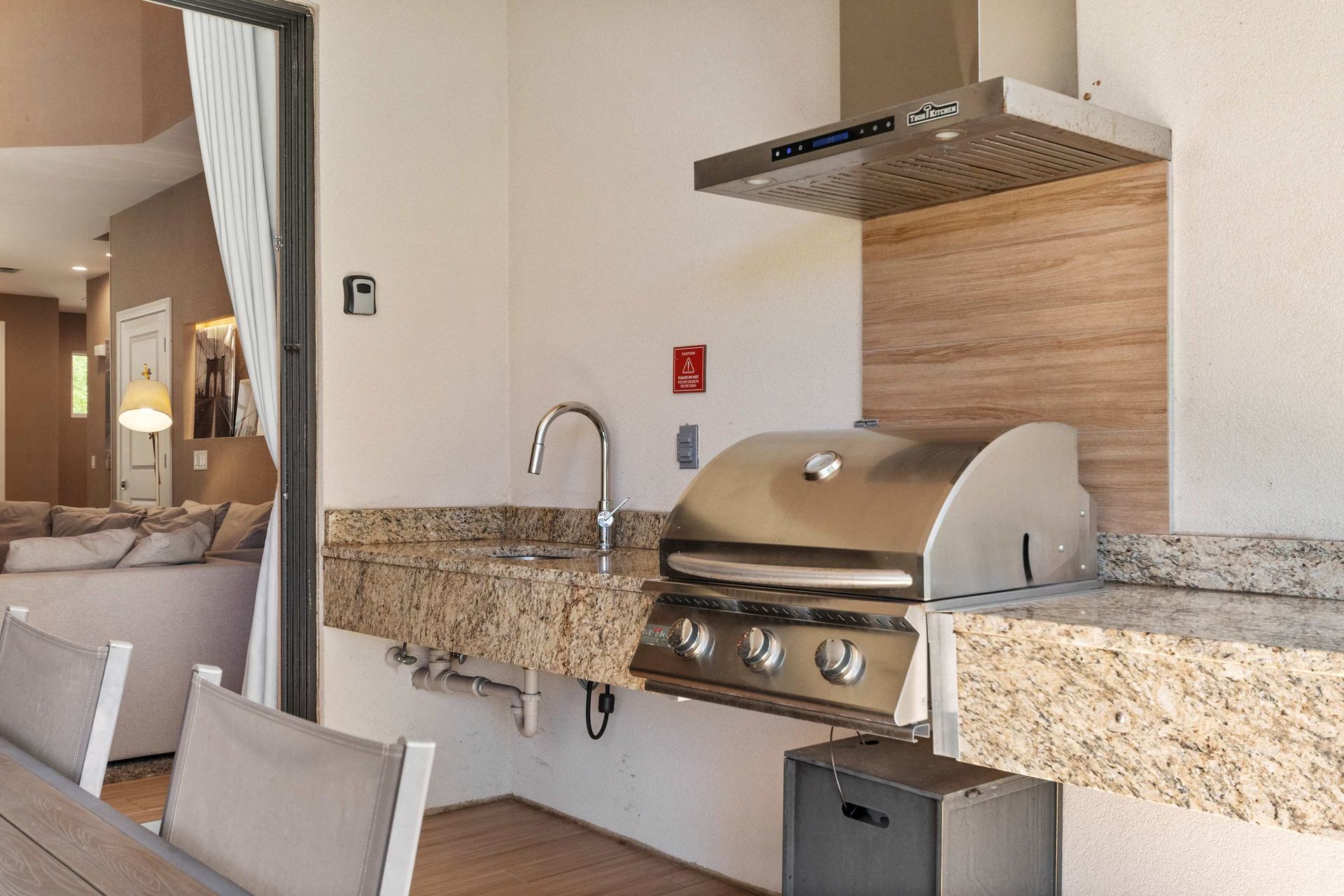 Modern outdoor grill station with granite countertops, sink, and seamless indoor access
