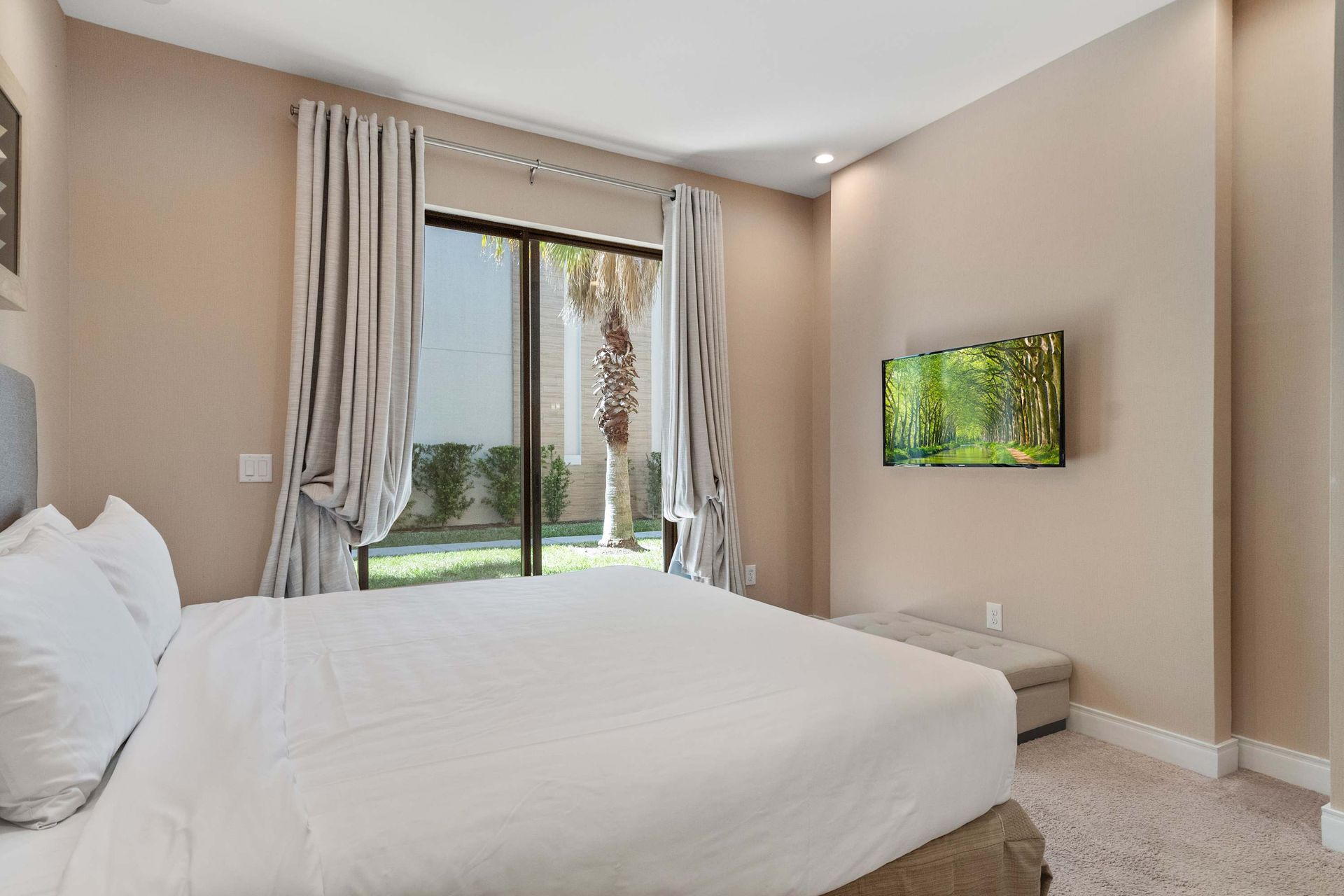 Serene bedroom with garden views, wall-mounted TV, and calming neutral tones
