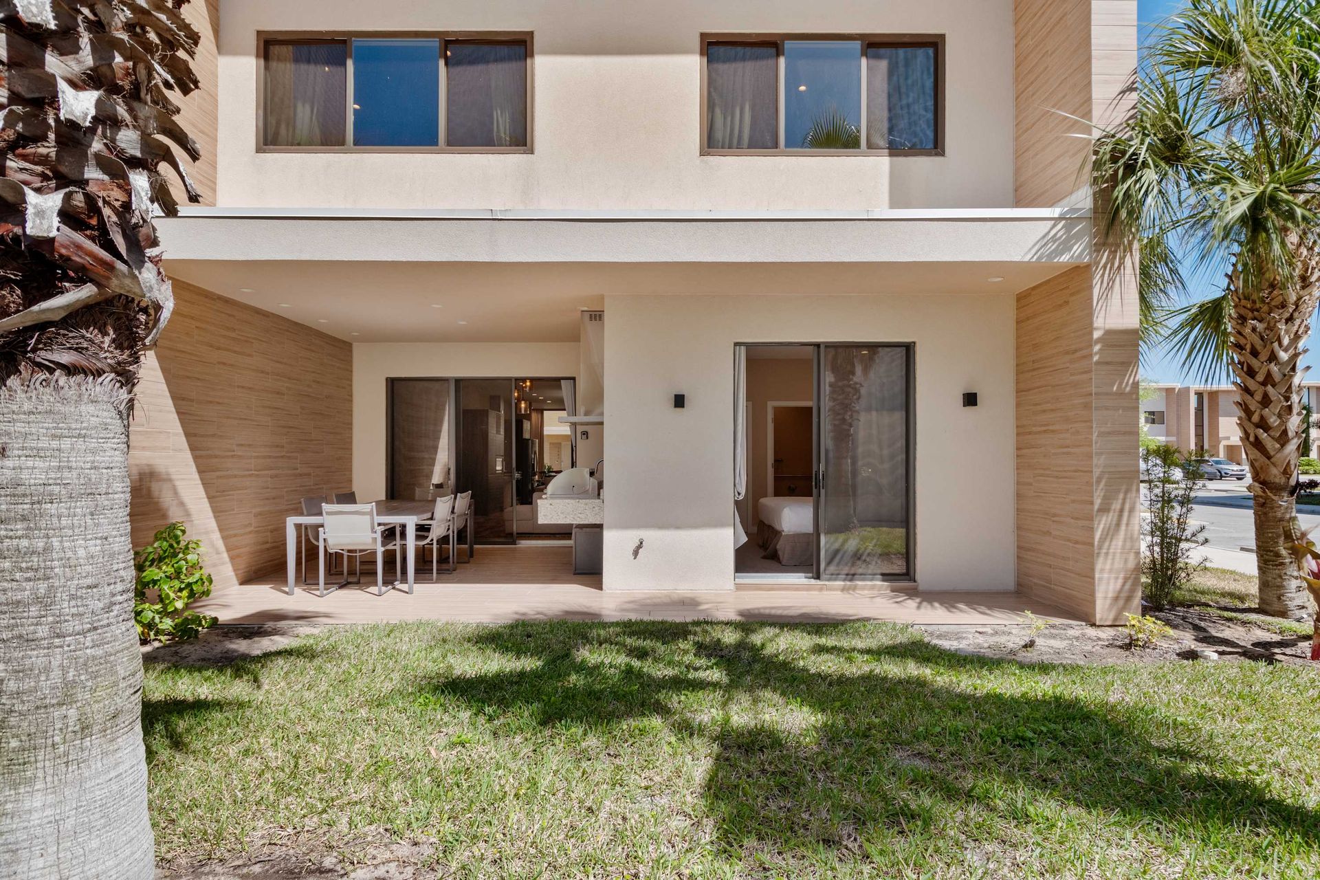 Spacious backyard with covered patio, outdoor dining, and tropical palm views
