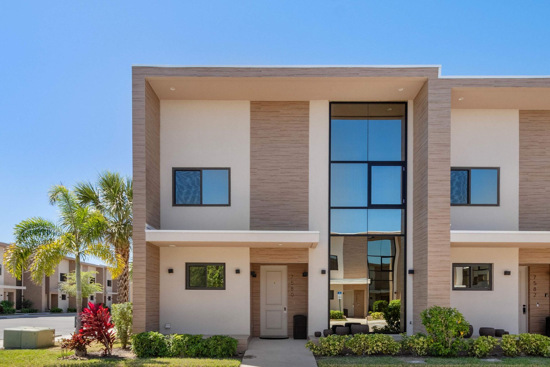 Modern townhouse with sleek design, large windows, and tropical landscaping
