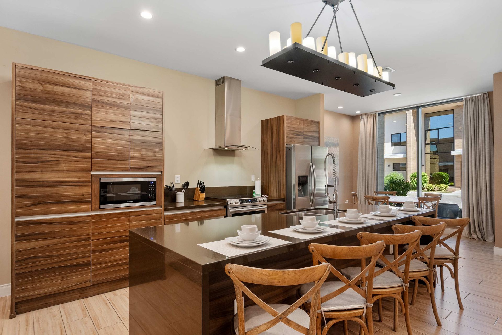 Stylish chef’s kitchen with island seating, rich wood finishes, and sunny views
