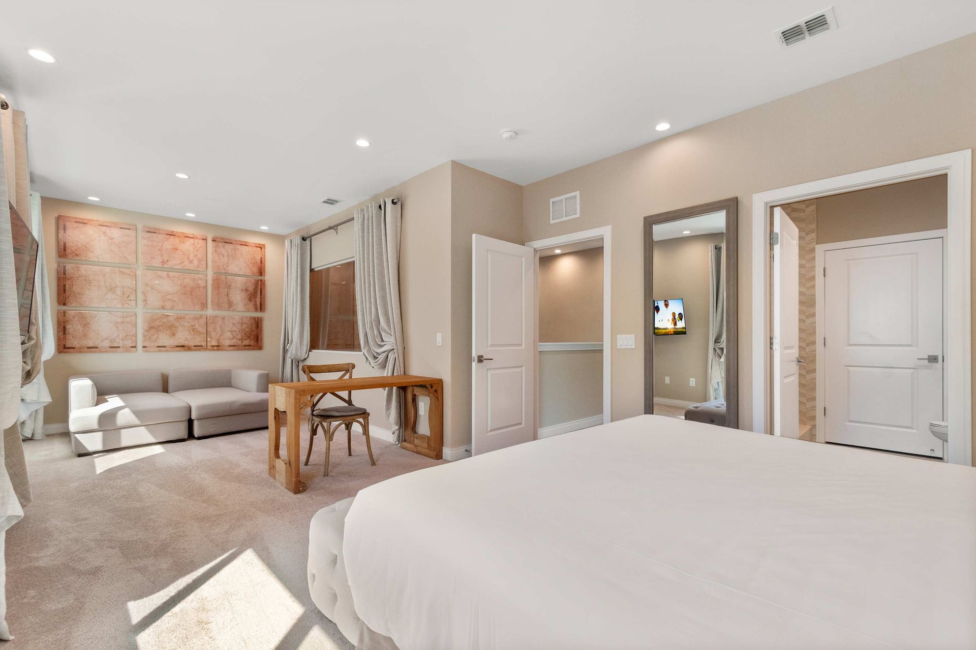 Spacious bedroom suite with cozy seating area, workspace, and warm natural light

