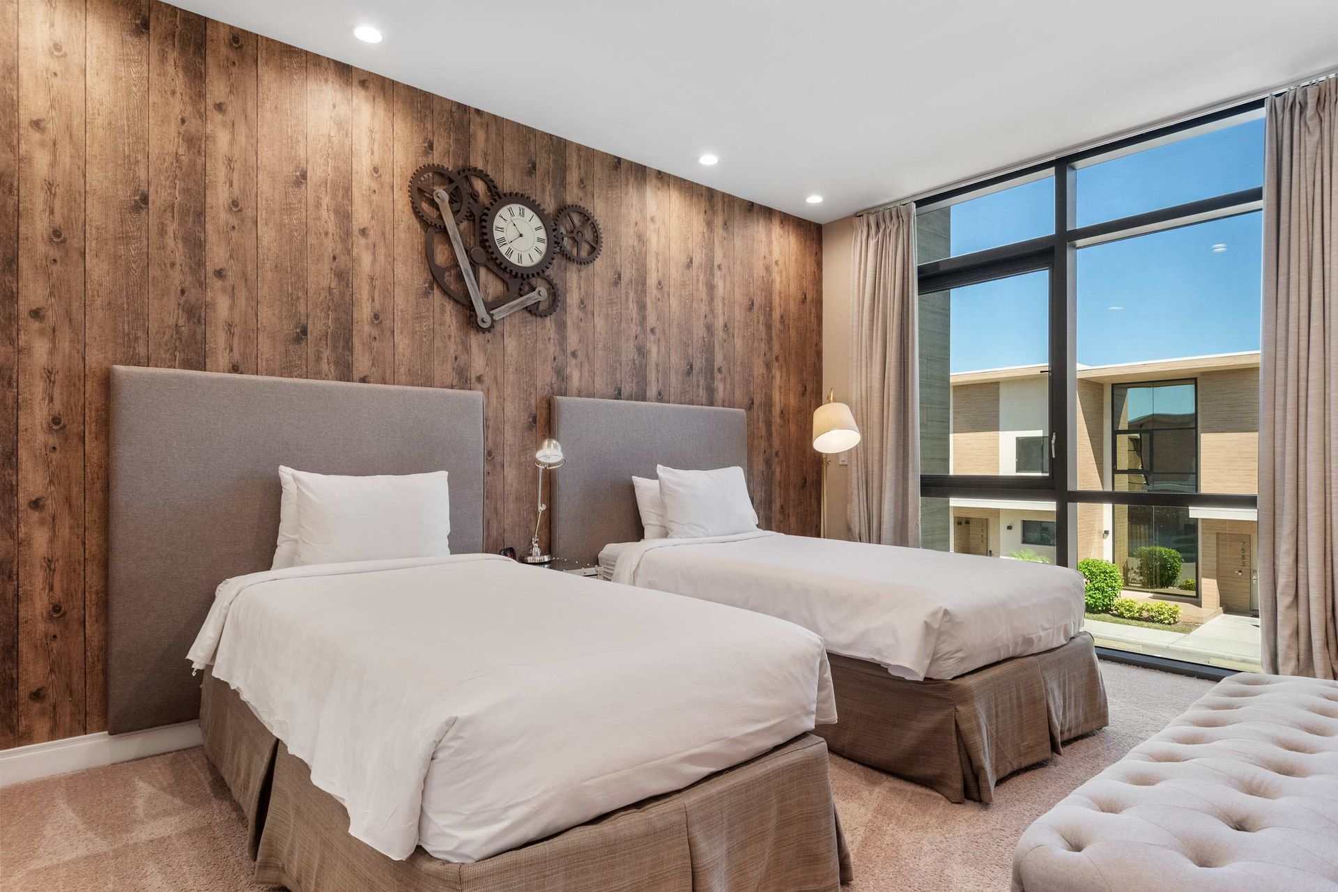 Stylish twin room with wood accent wall, large window, and cozy modern touches
